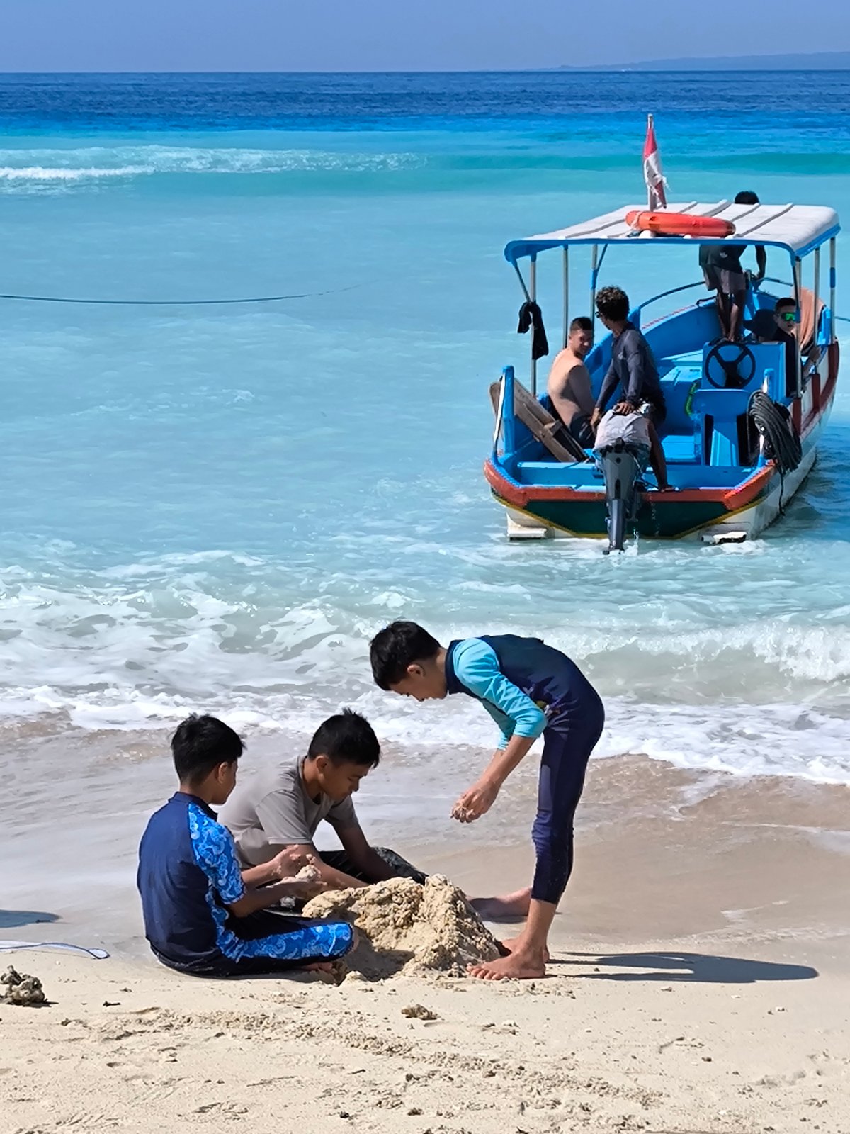 Lazy morning on an Indonesian beach with boats, kids, and food