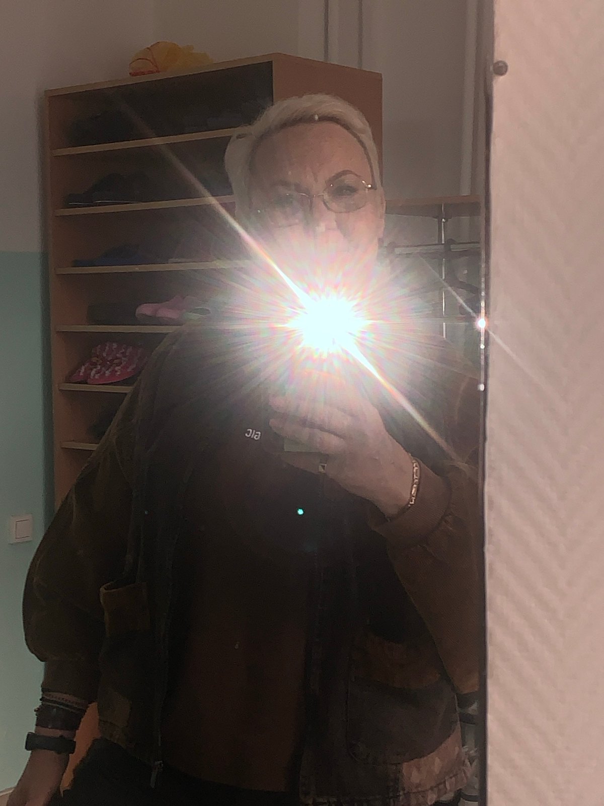 Elderly person in brown jacket observed in mirror reflection