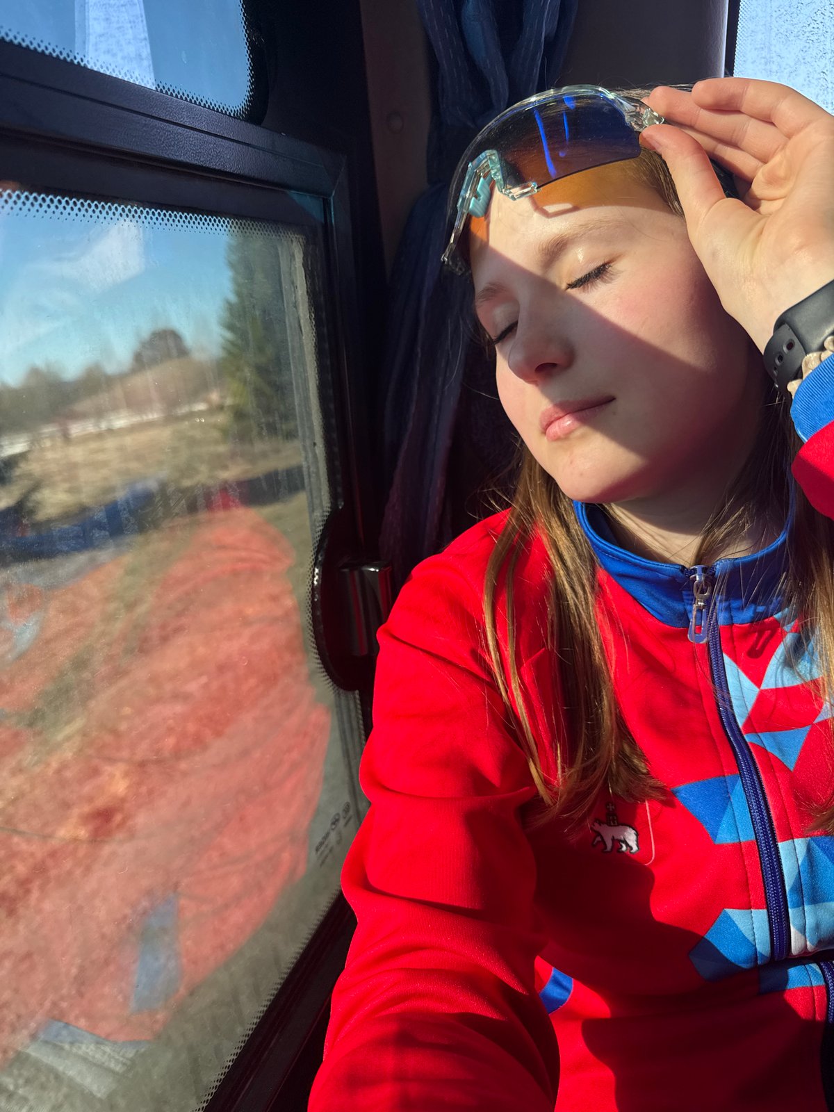 Young person rests in vehicle wearing colorful jacket, Челва