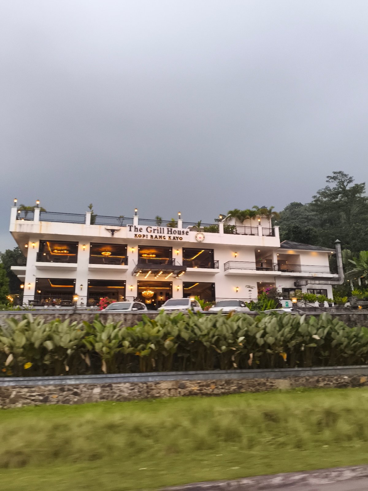 Morning traffic flows past cafes on tree-lined Babakan Madang road