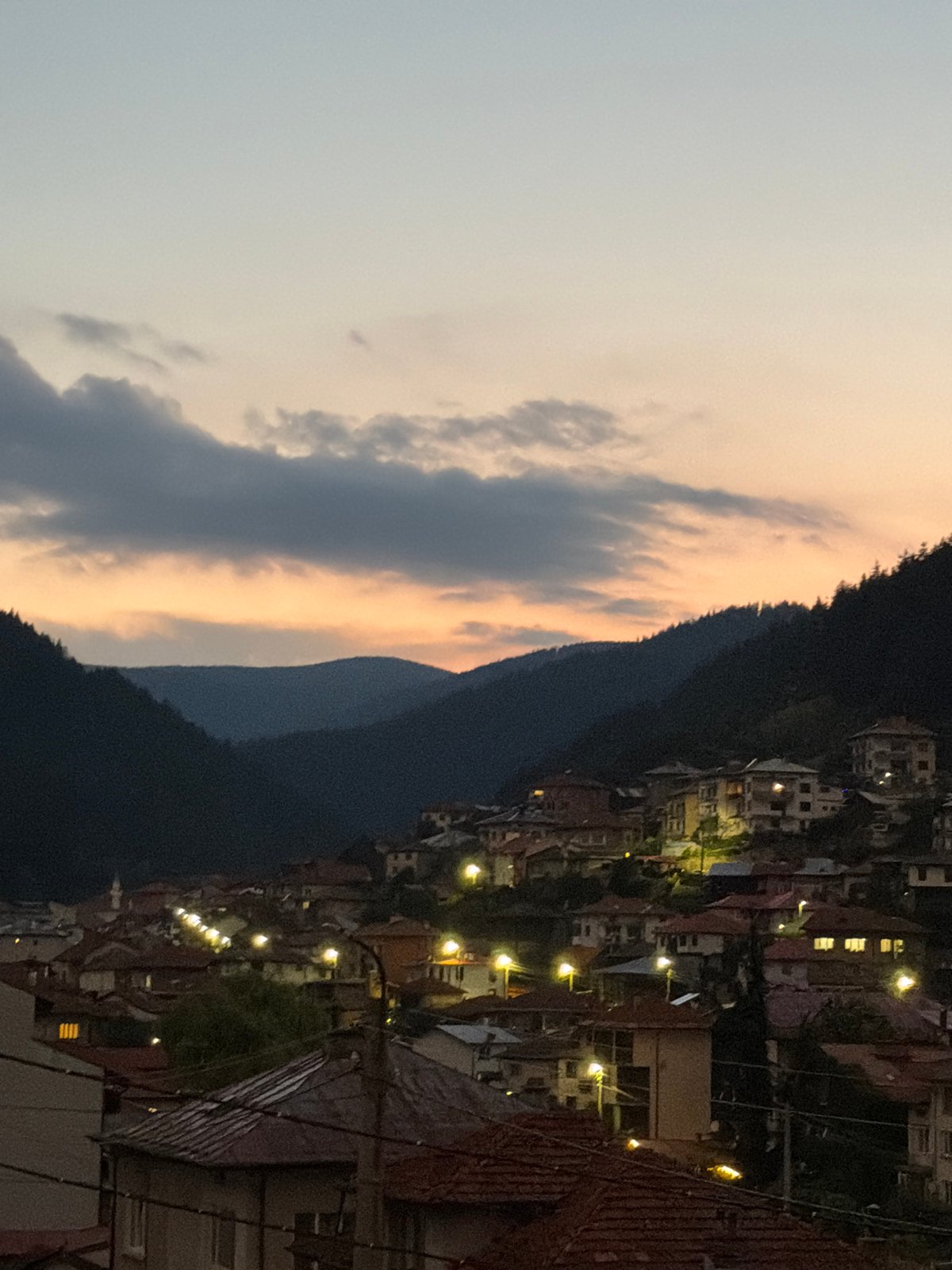Hillside town silhouetted against a dusky orange sunset