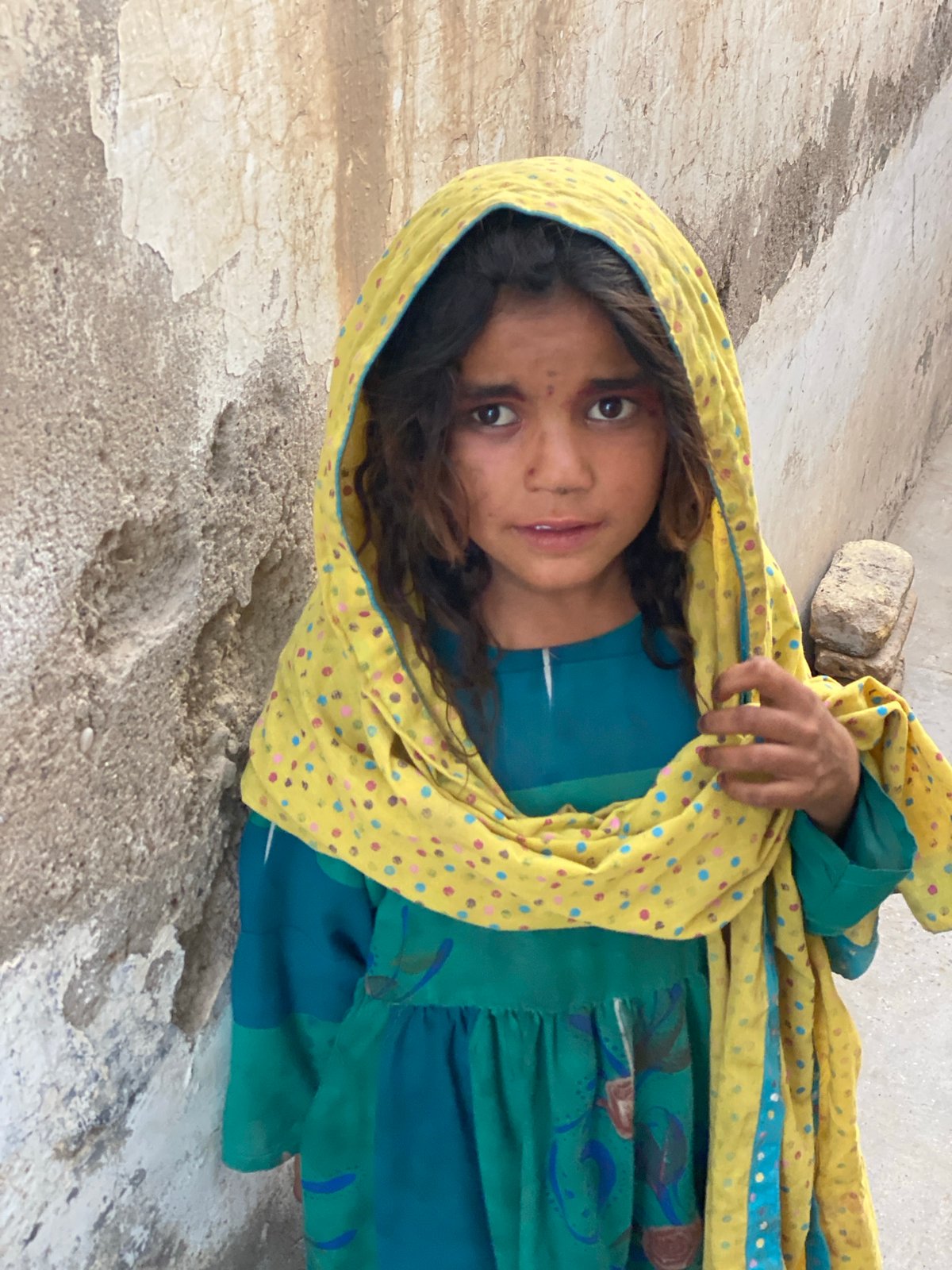 Teal dress against a weathered wall in Kandahar