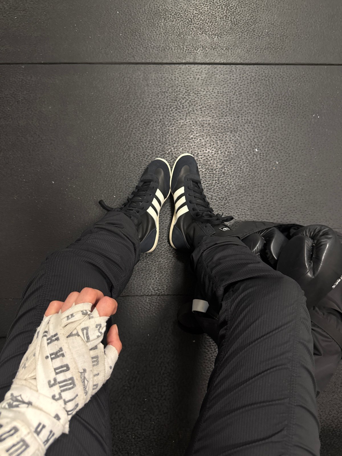Person in Adidas shoes sits on gym mat in London