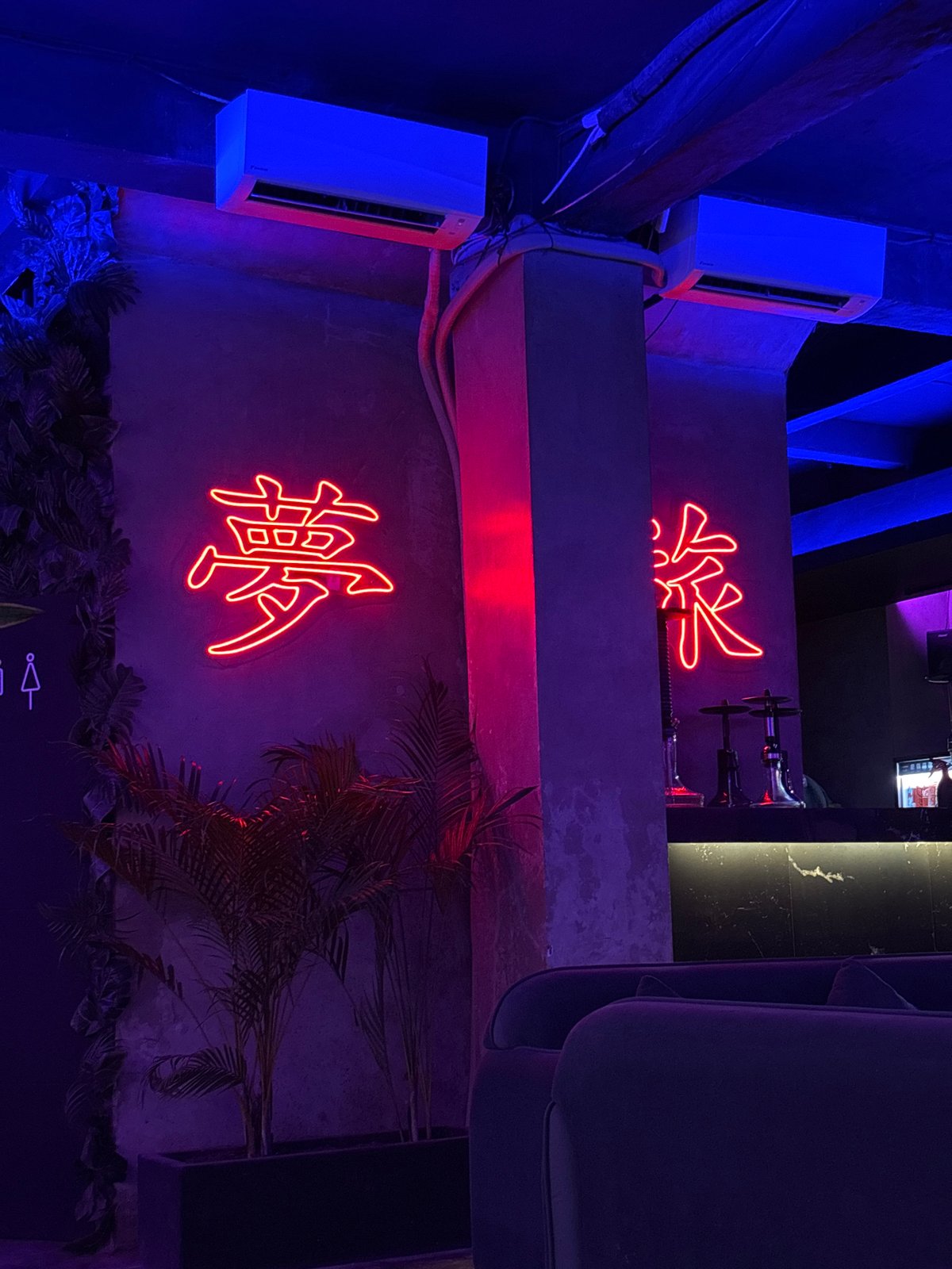 Bar patron documents neon-lit lounge with hookah in Kuta Selatan