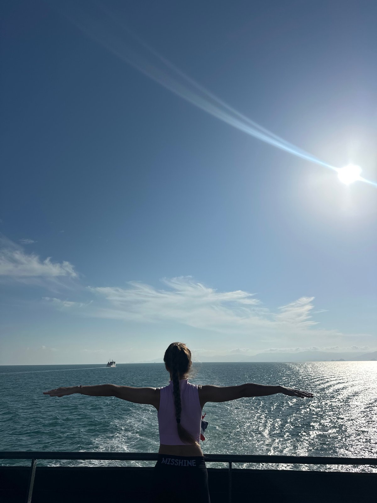 Arms wide on a sun-drenched ferry deck, Gulf of Thailand
