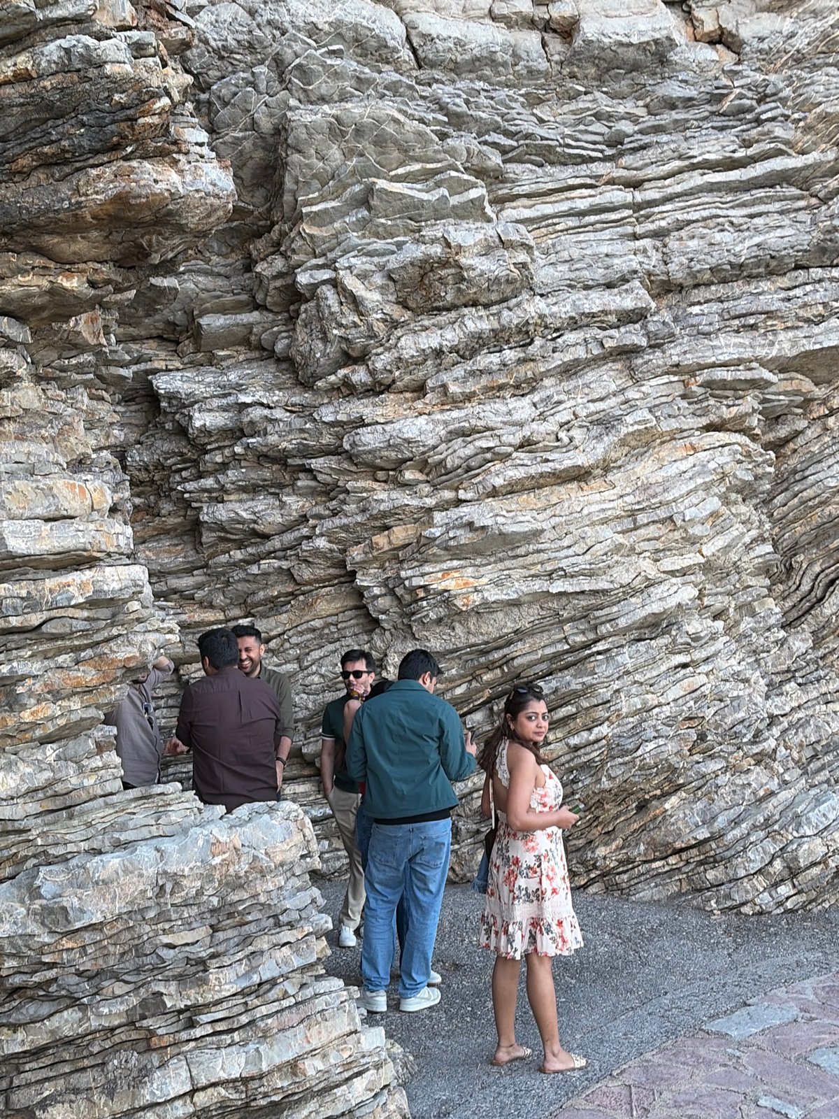 Tourists pose at scenic Budva cliff formation during sunset