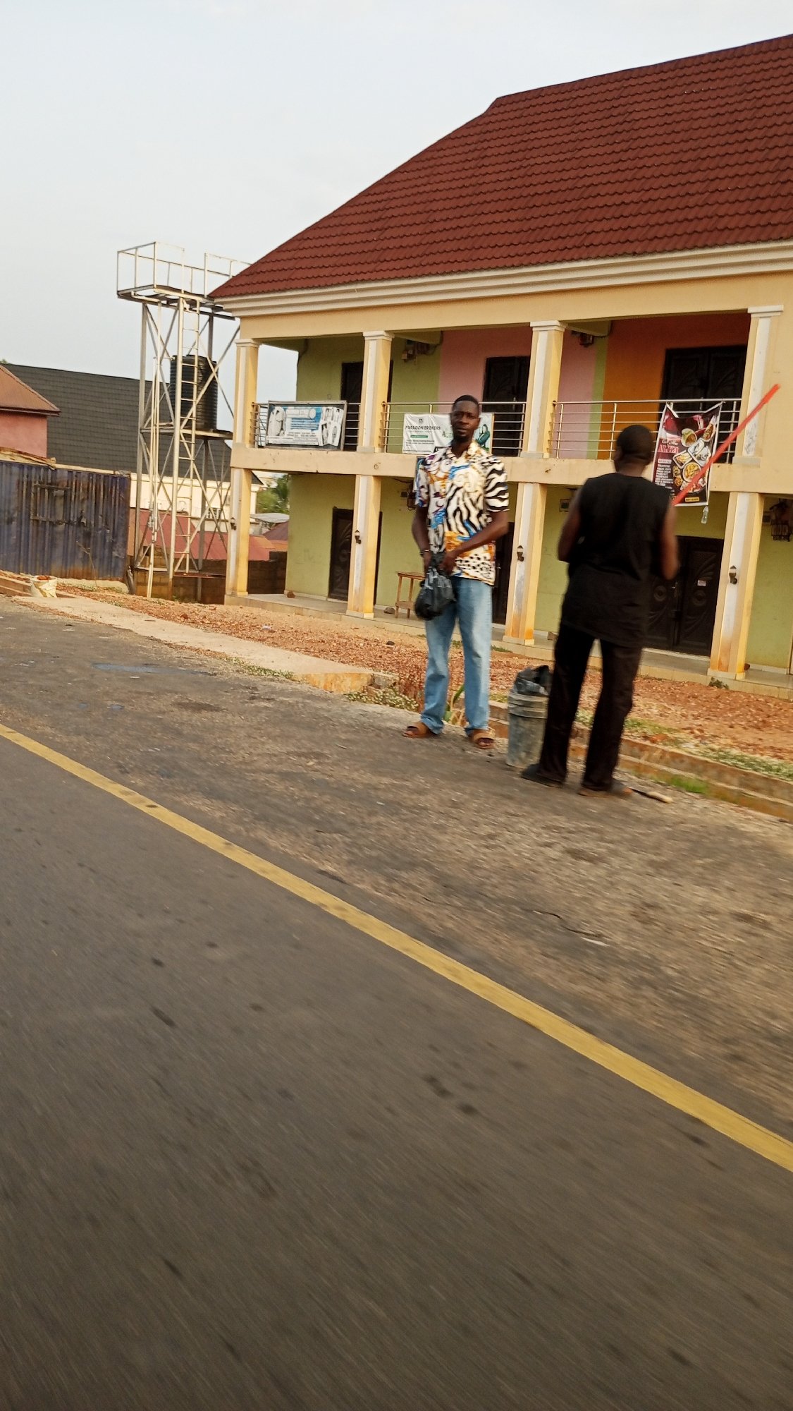 Men gather on roadside near motorcycle in Zango-ndaji