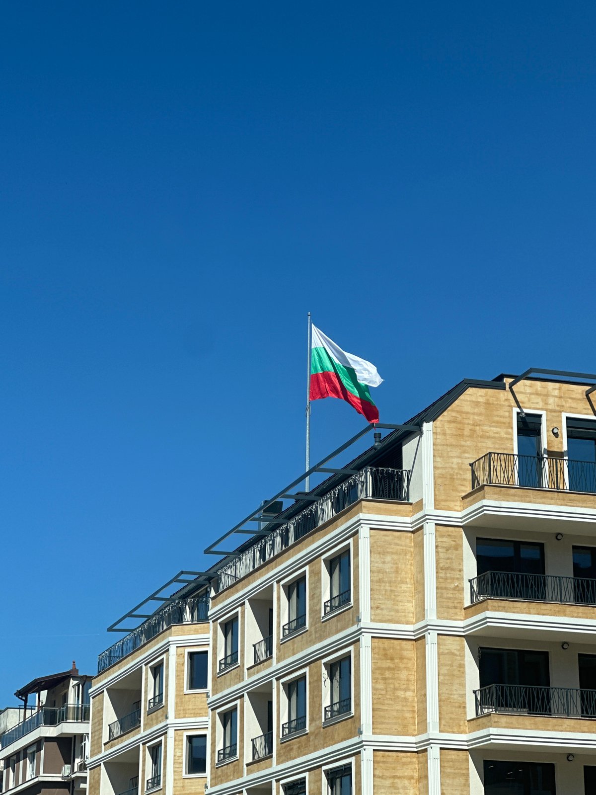 Bulgarian flag flies over Sofia building under clear skies