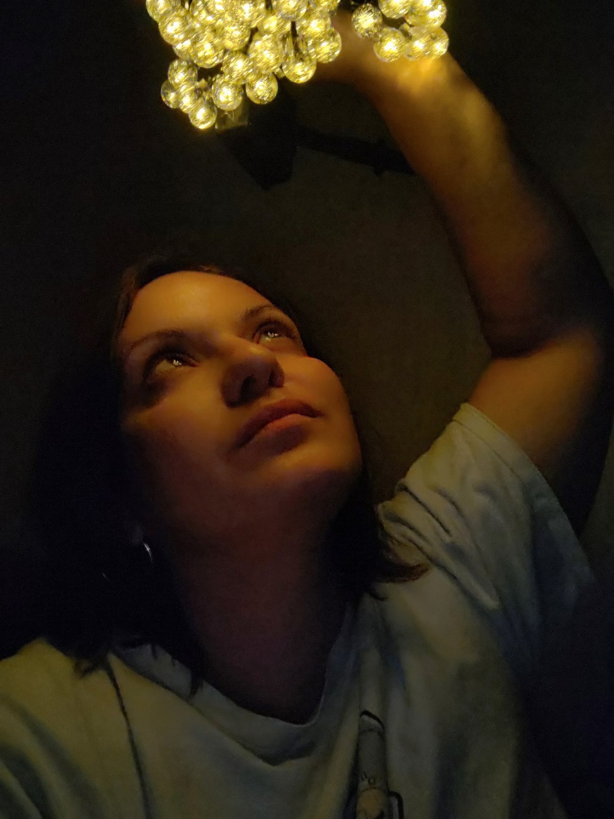 Woman holds fairy lights in dimly lit indoor space