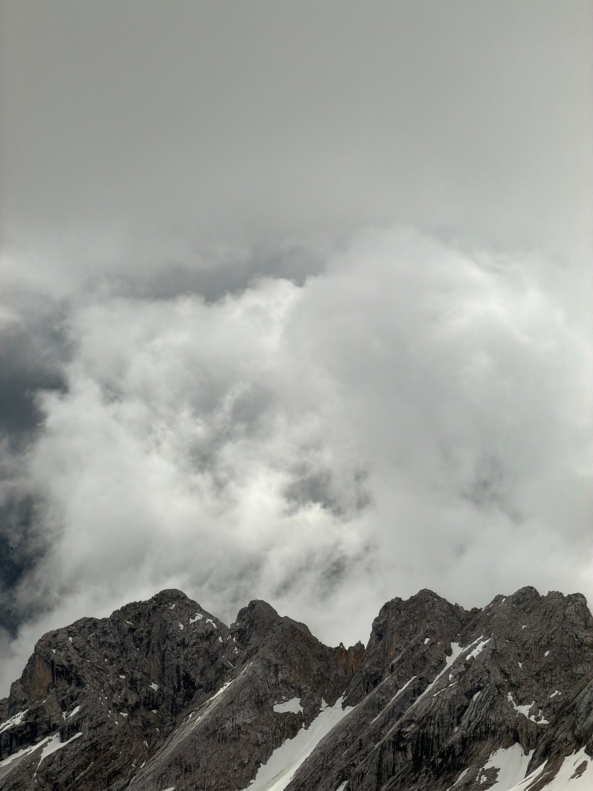 Cloudy mountain landscape with snow patches observed in Austria