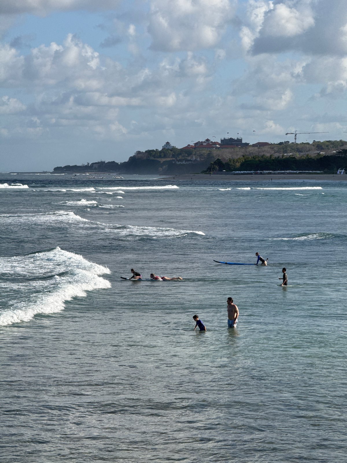 Surf and bougainvillea on a cloudy morning in Kuta Selatan