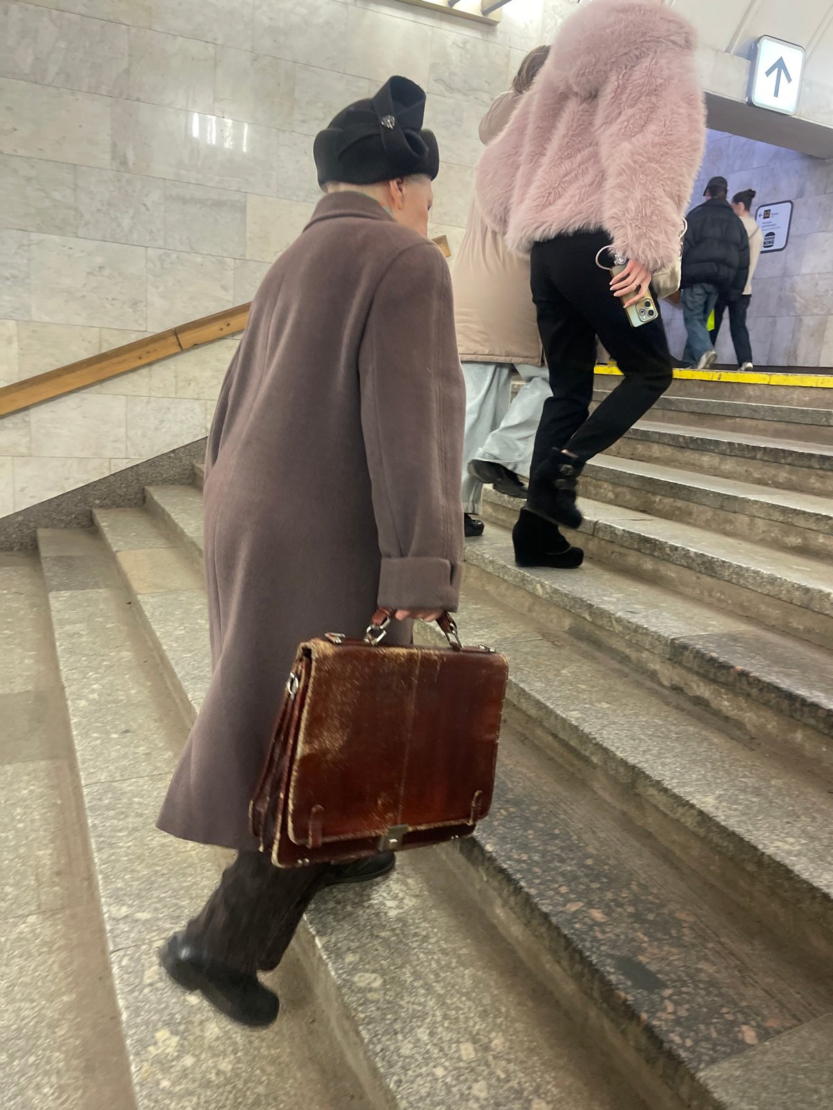Person climbs stairs in busy Moscow metro station