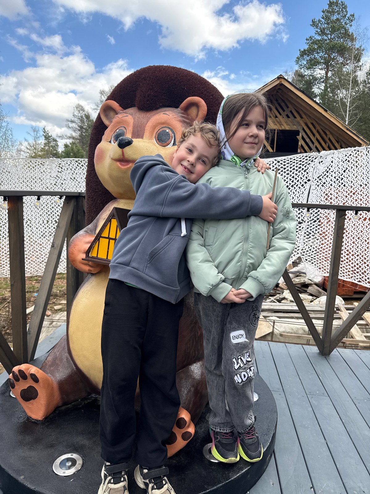 Children play on bear statue near A-frame cabin in Divnogorsk