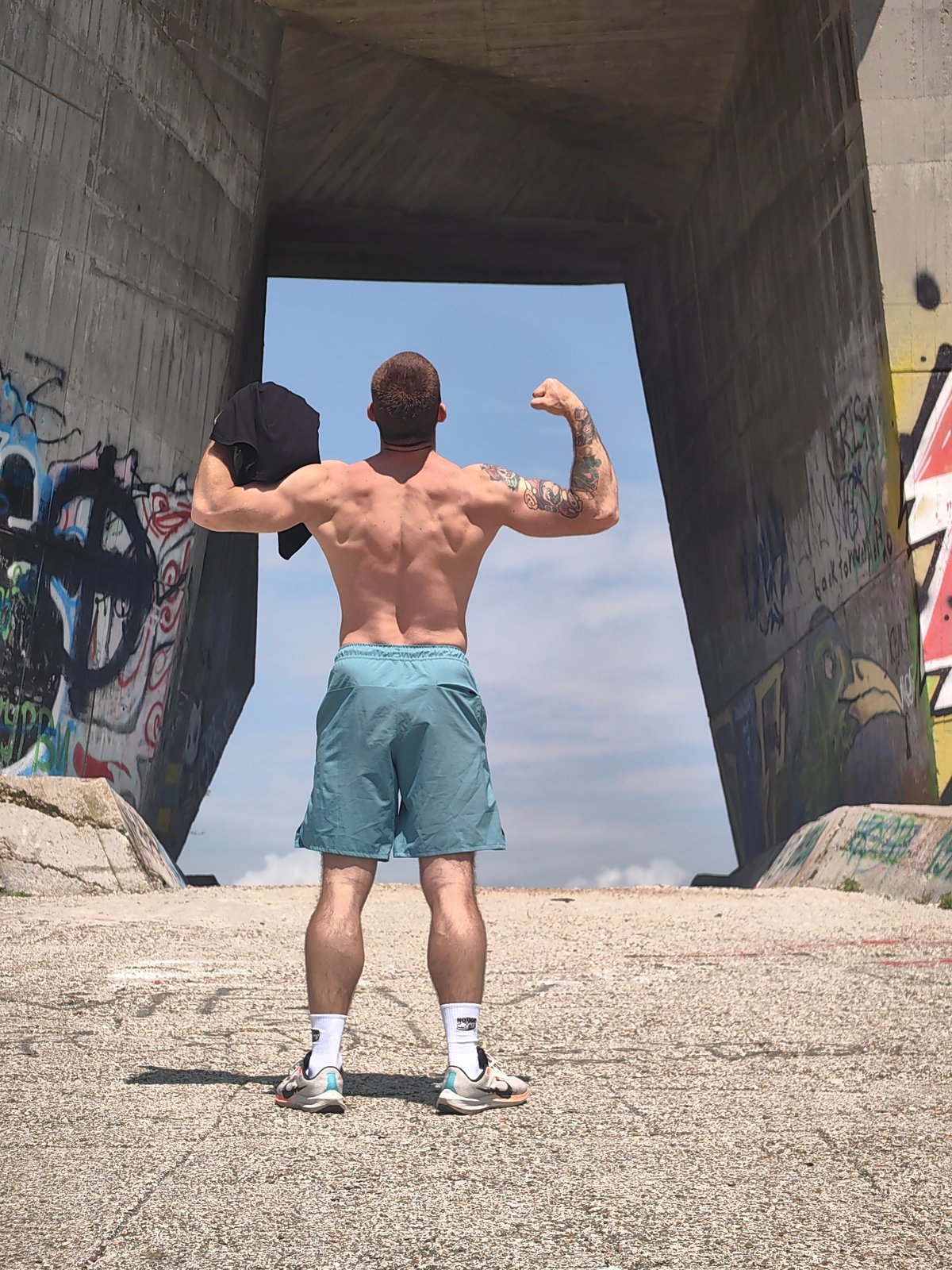 Man poses shirtless under concrete structure in Varna