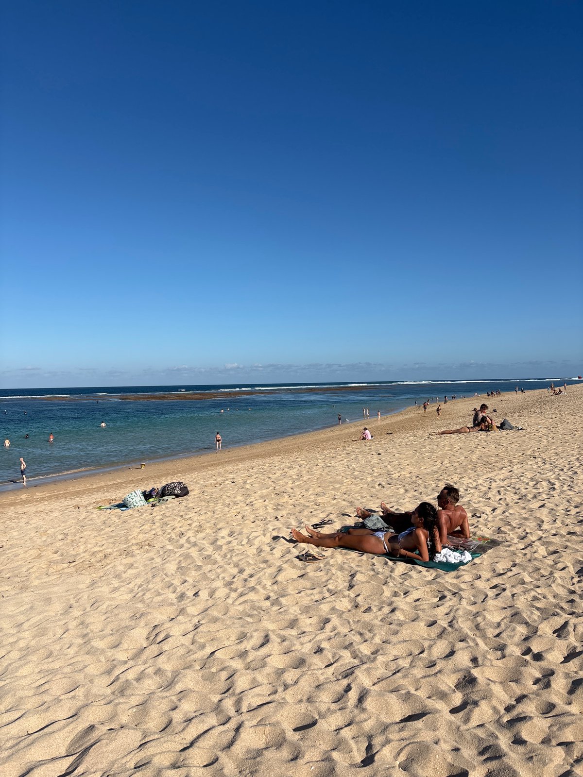 Morning beach activities unfold under clear skies in Kuta Selatan