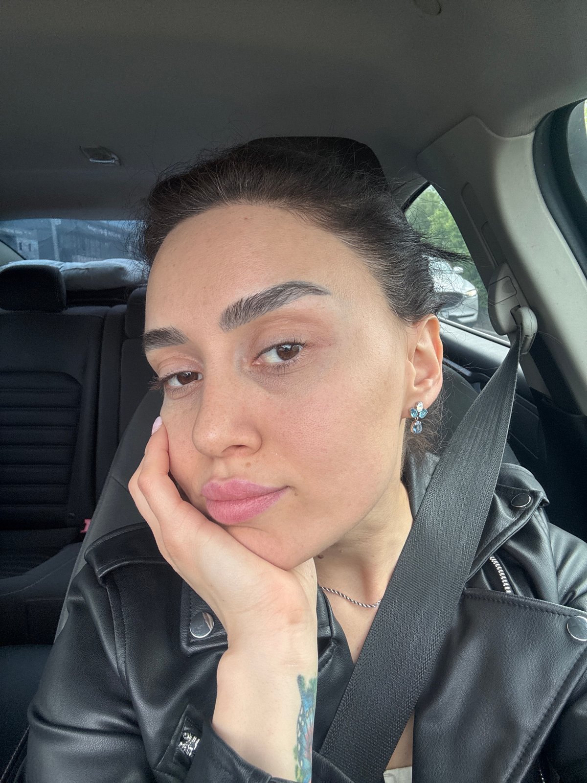 Woman rests in car wearing leather jacket in Tbilisi
