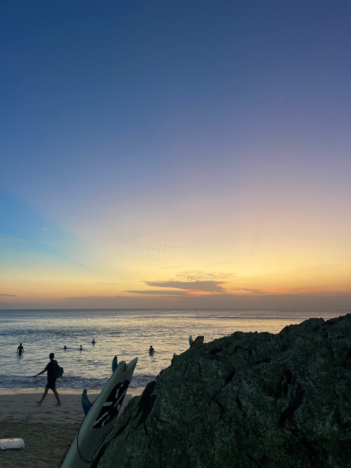 Sunset beach day with surfers and dogs at Kuta Selatan