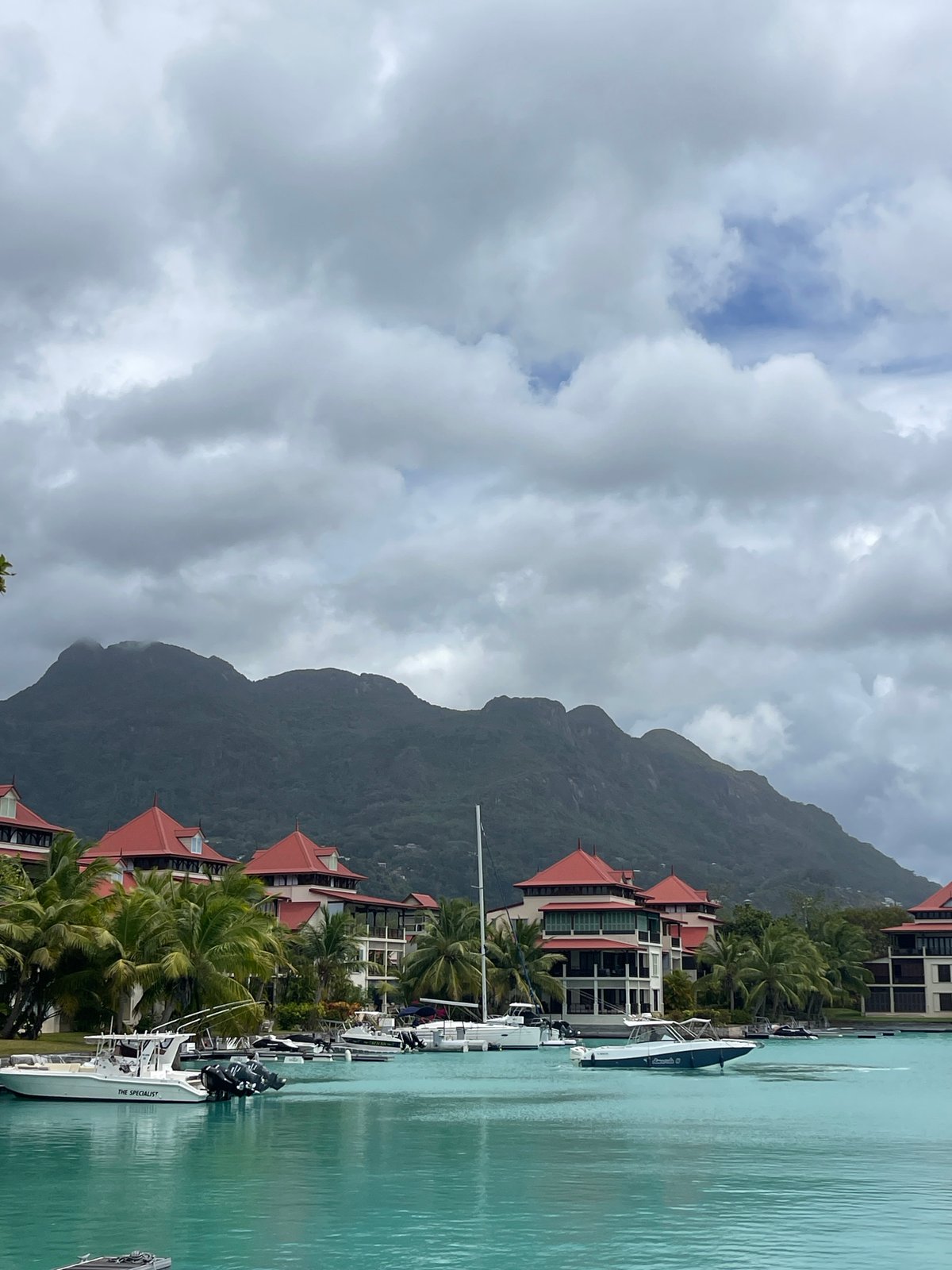 Calm Seychelles bay with red-roofed buildings and moored boats