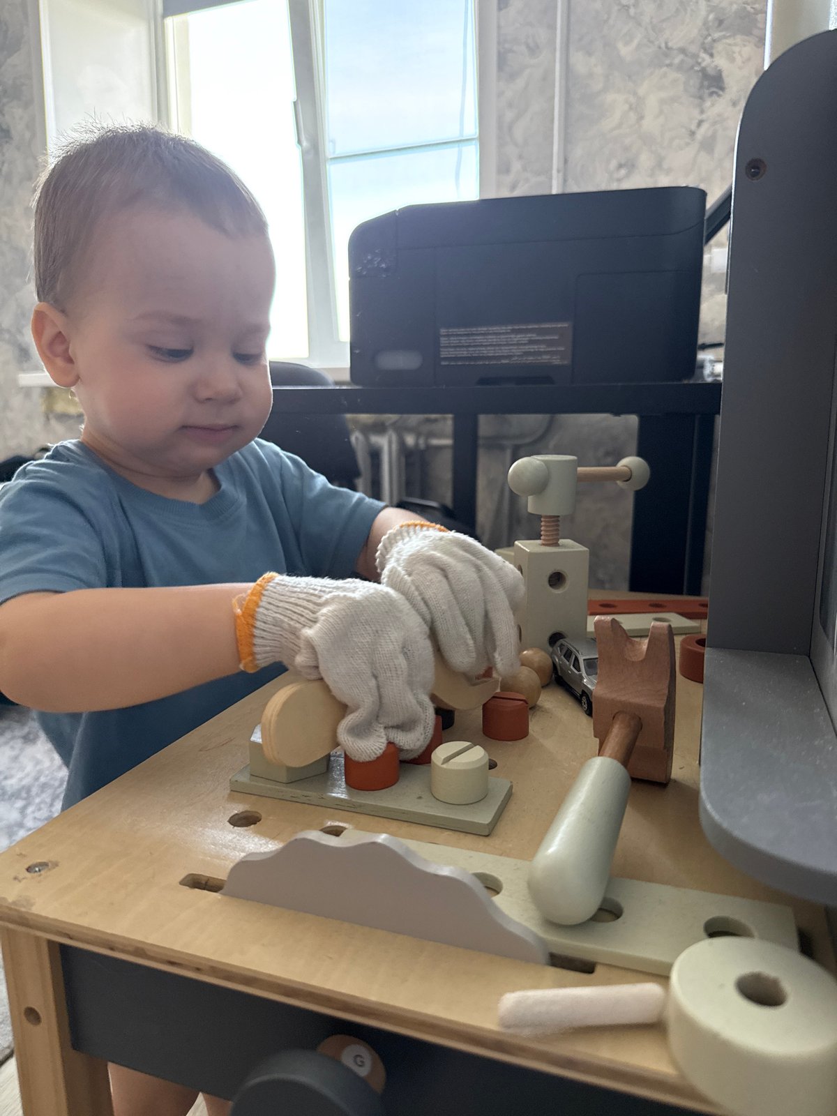 Child plays with wooden toy workbench in Rusanovo
