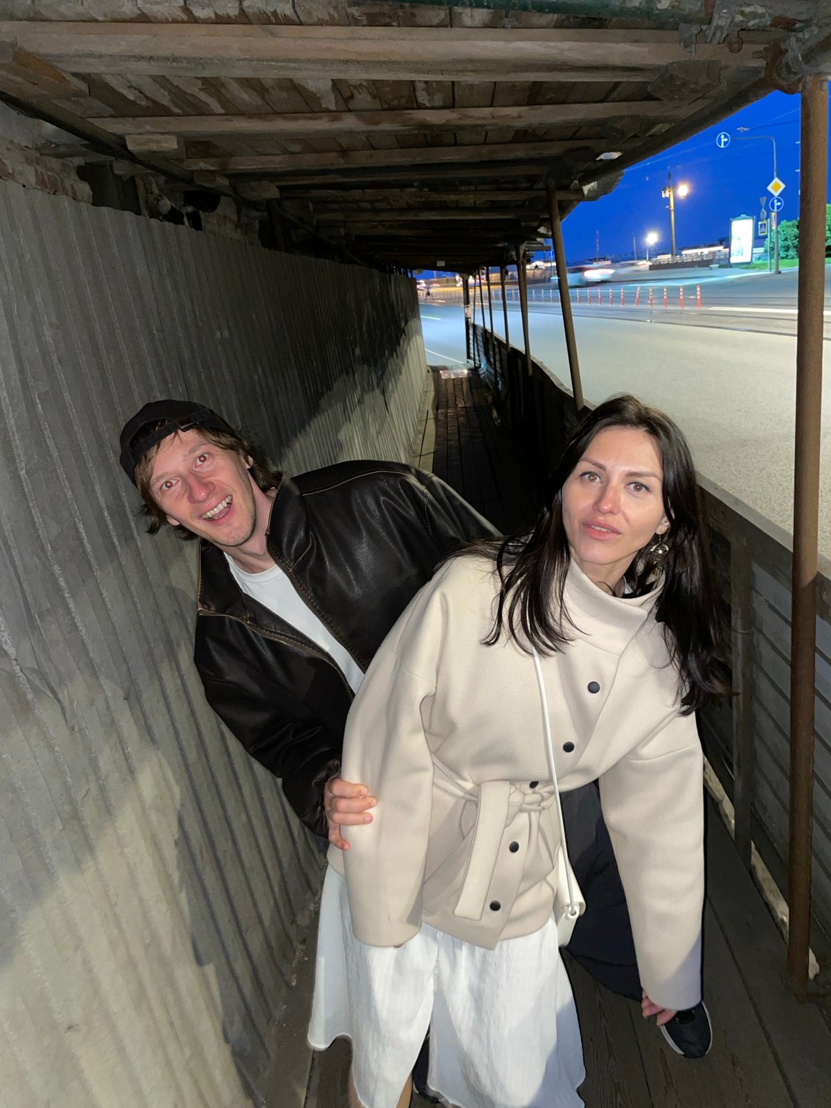 Couple poses, walks near covered walkway in Saint Petersburg