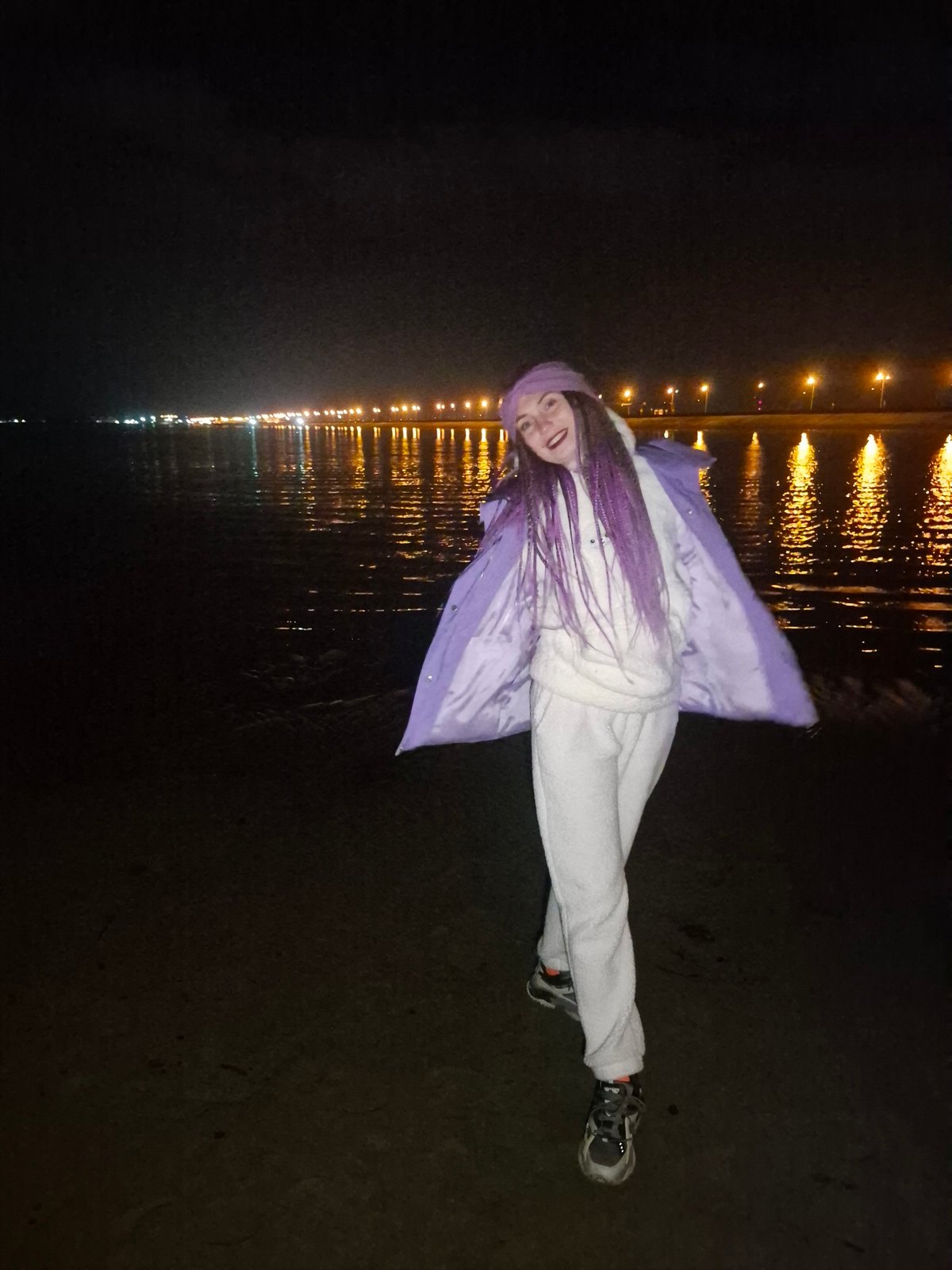 Person photographed lying by illuminated waterfront in Noviy, Russia