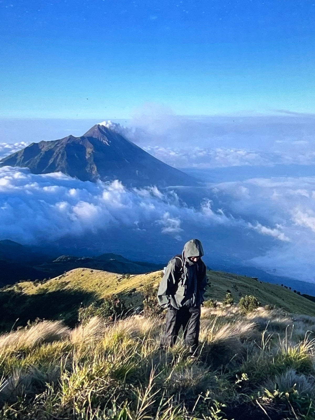Hiker observed on mountain overlook viewing cloud-covered peaks