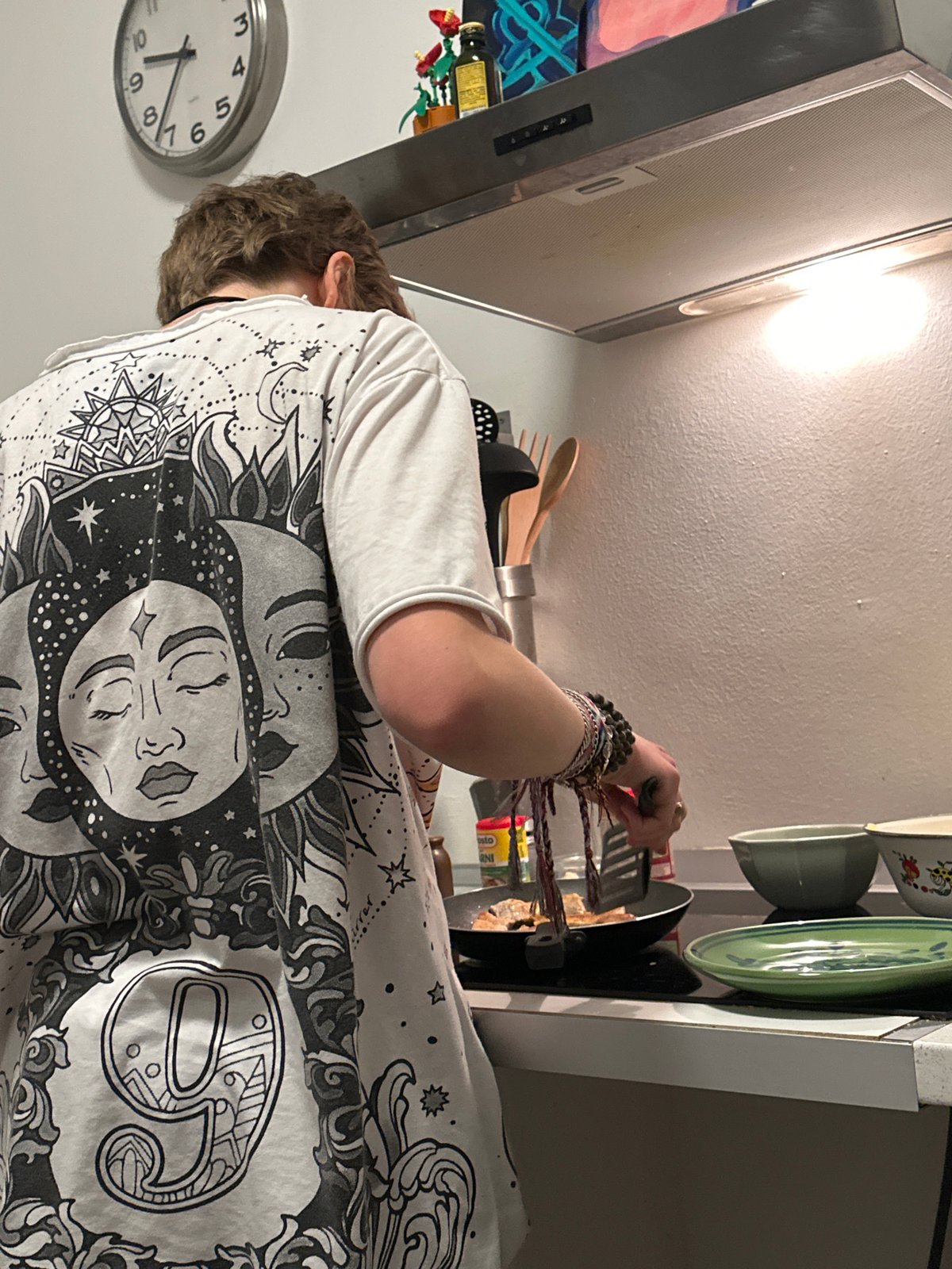 Person cooks dinner in Milan kitchen wearing sun-design shirt