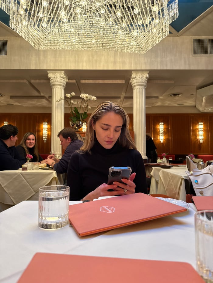 Woman checks phone at restaurant table in New York