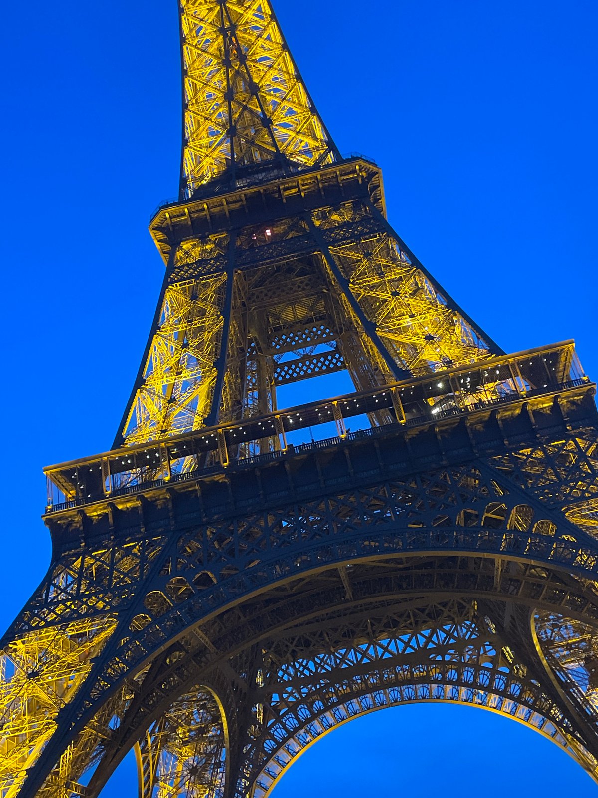 Evening crowds gather at Champ de Mars for illuminated Eiffel Tower views