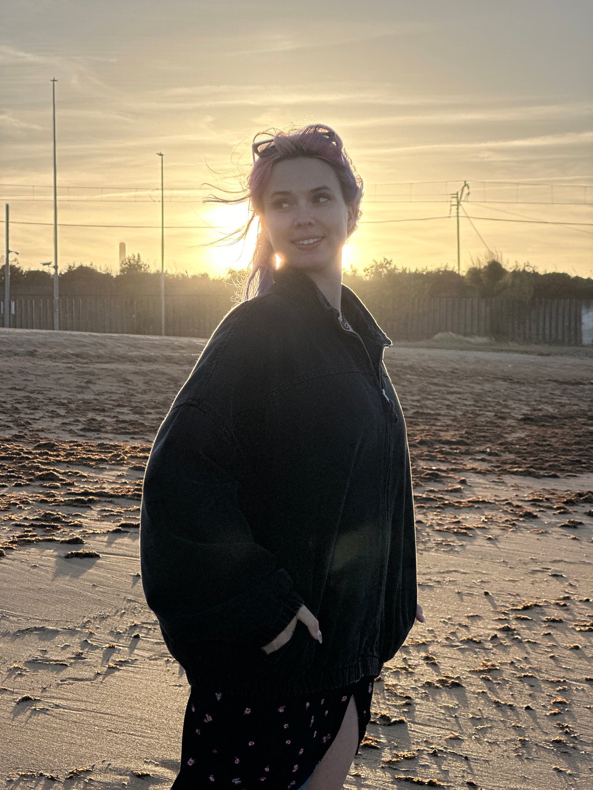 Purple-haired woman enjoys sunset beach walk with dog in Gijón