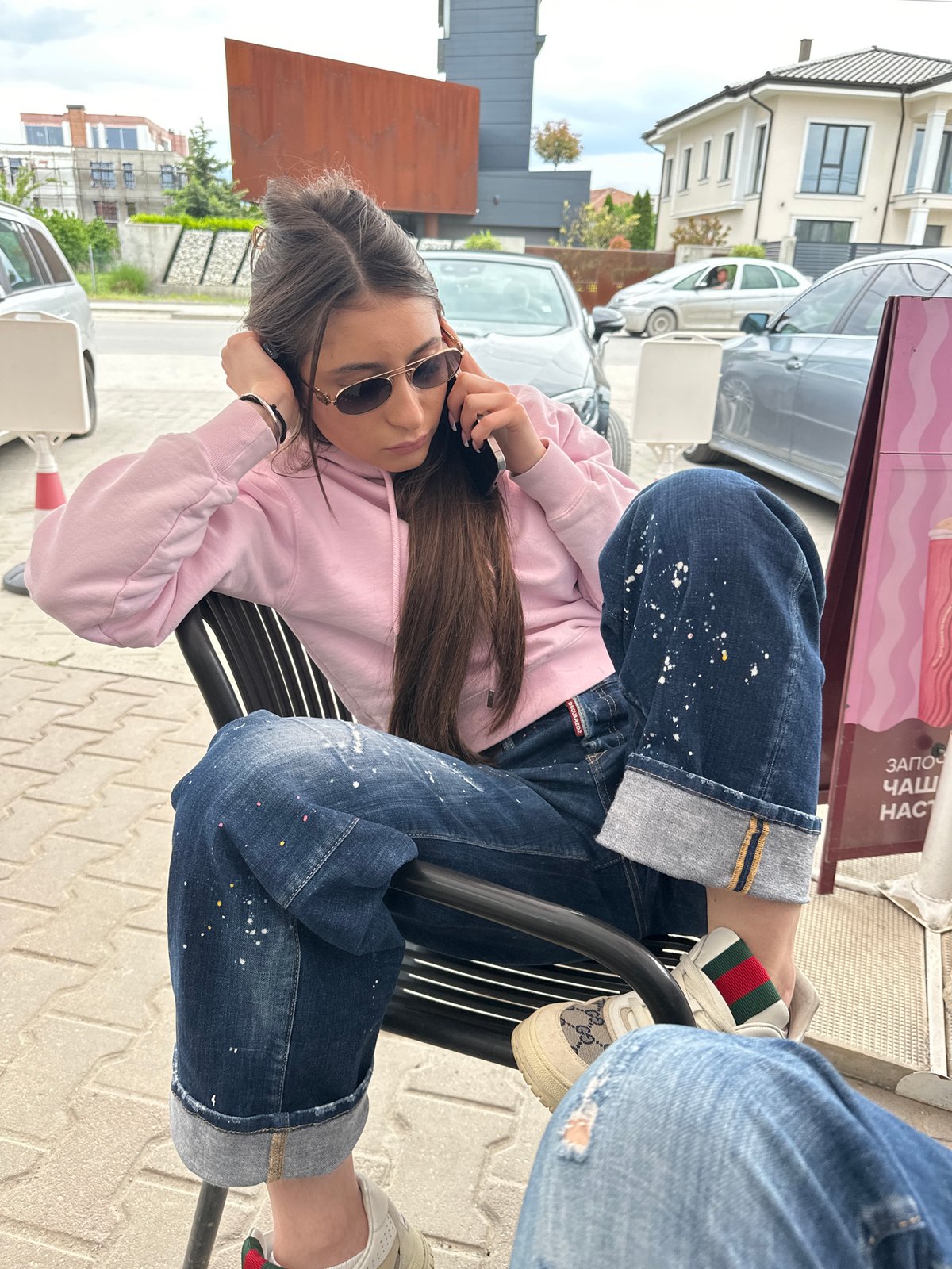Woman in paint-splattered jeans relaxes at Plovdiv café
