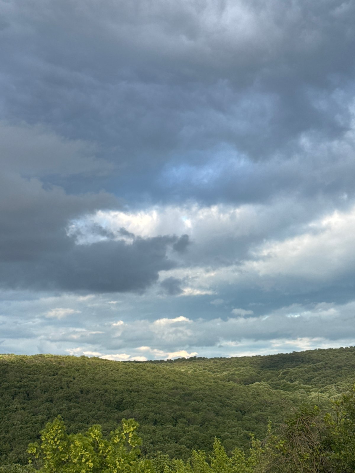 Full rainbow appears over Bulgarian countryside during cloudy afternoon