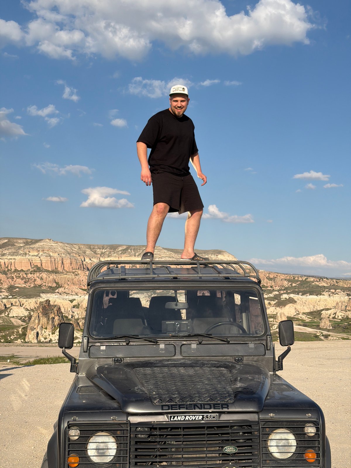 Man poses on Land Rover in Göreme's geological landscape