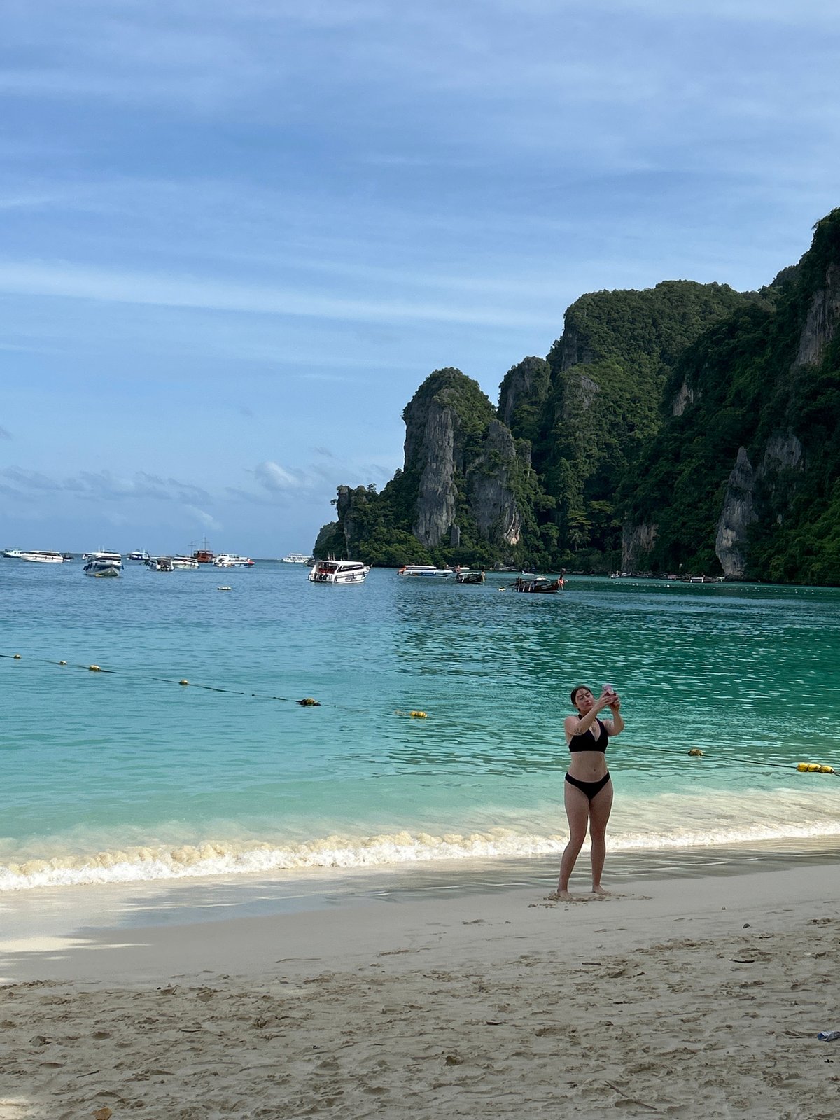 Morning beach scene at Ao Nang with tourists and ferry activity