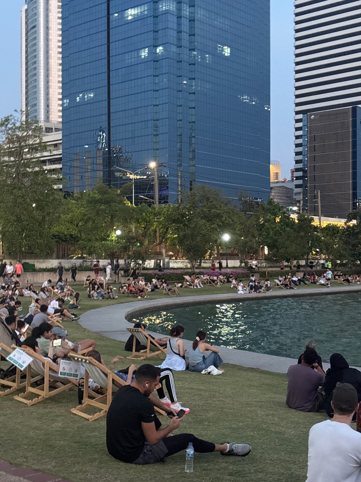 Bangkok residents enjoy routine park activities amid city skyline