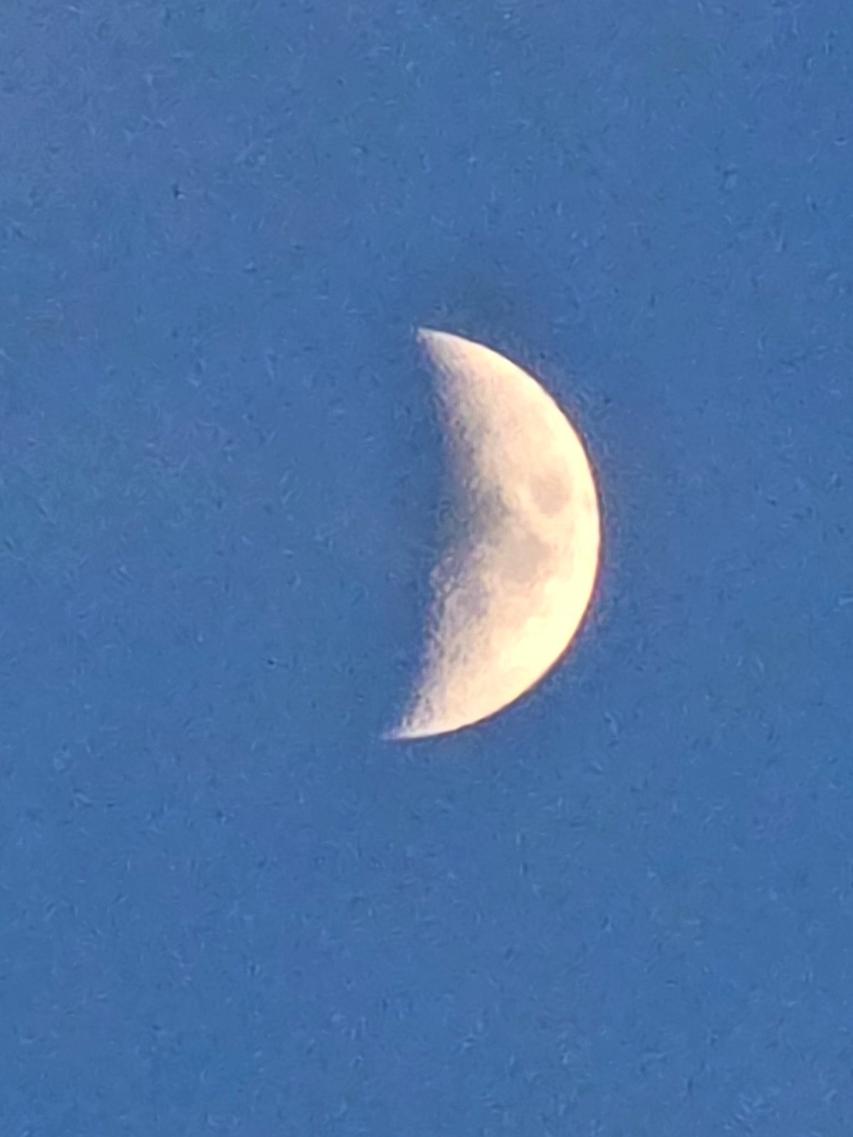 Dusk along a river dam, crescent moon rising overhead