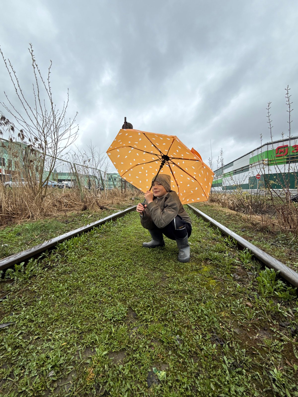 Umbrella moments captured near Dmitrov railway tracks during overcast weather
