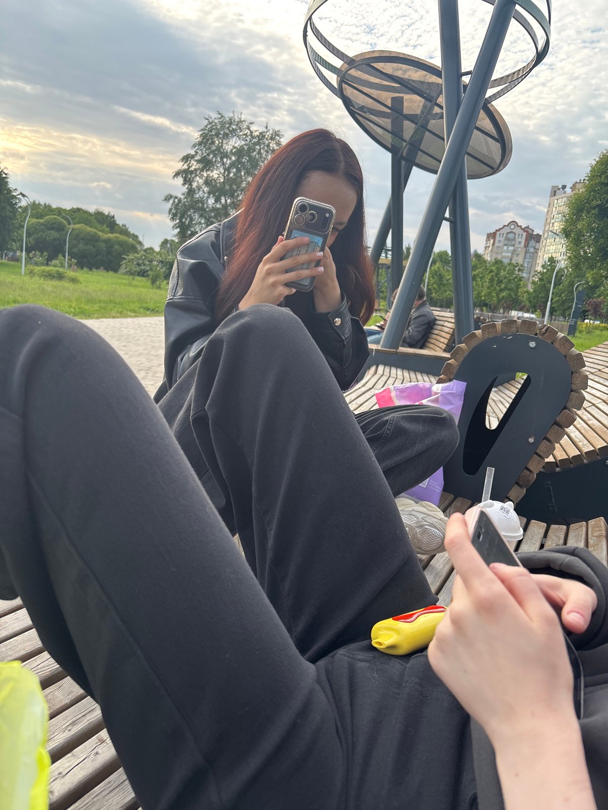 Two women take selfies on park bench in Sinyavino