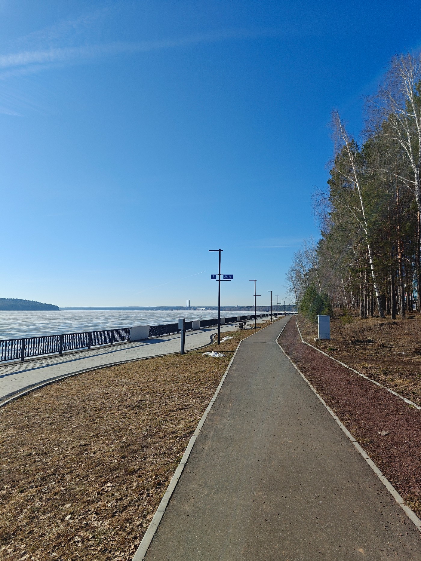 Early morning cyclist rides frozen reservoir path in Chaikovsky