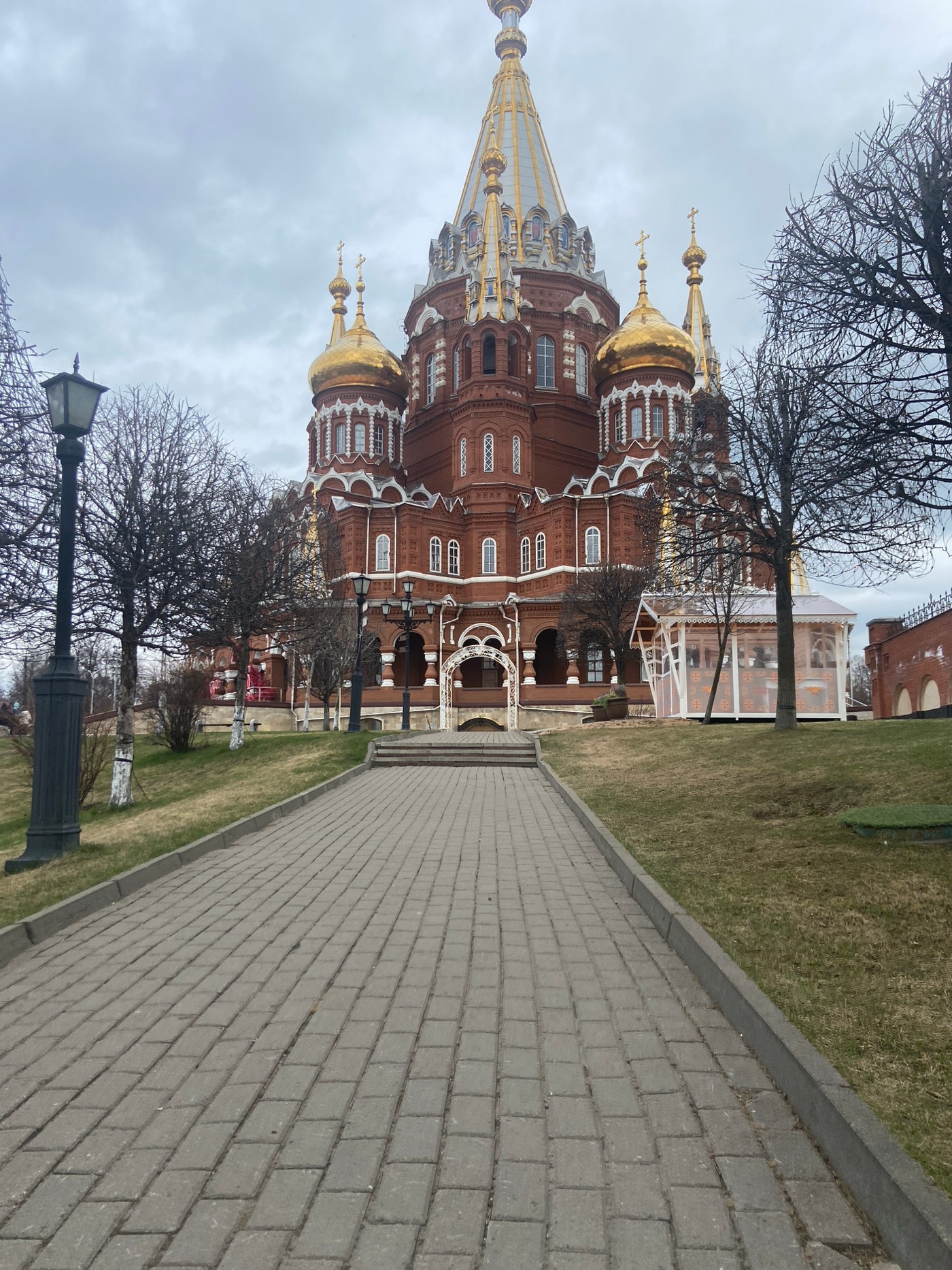 Brown brick building with golden domes observed under overcast sky