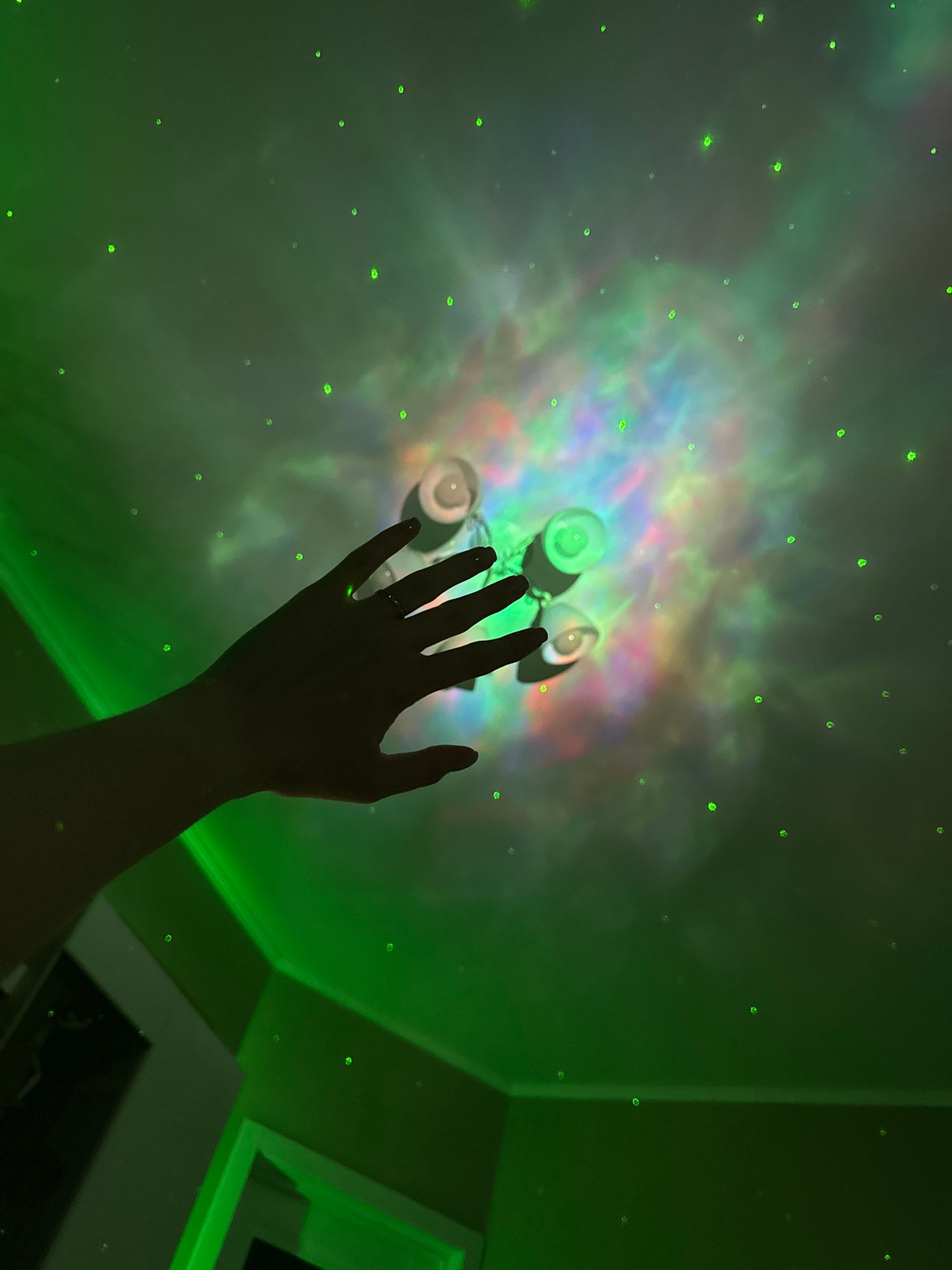 Galaxy projector and mood lighting fill a decorated bedroom.