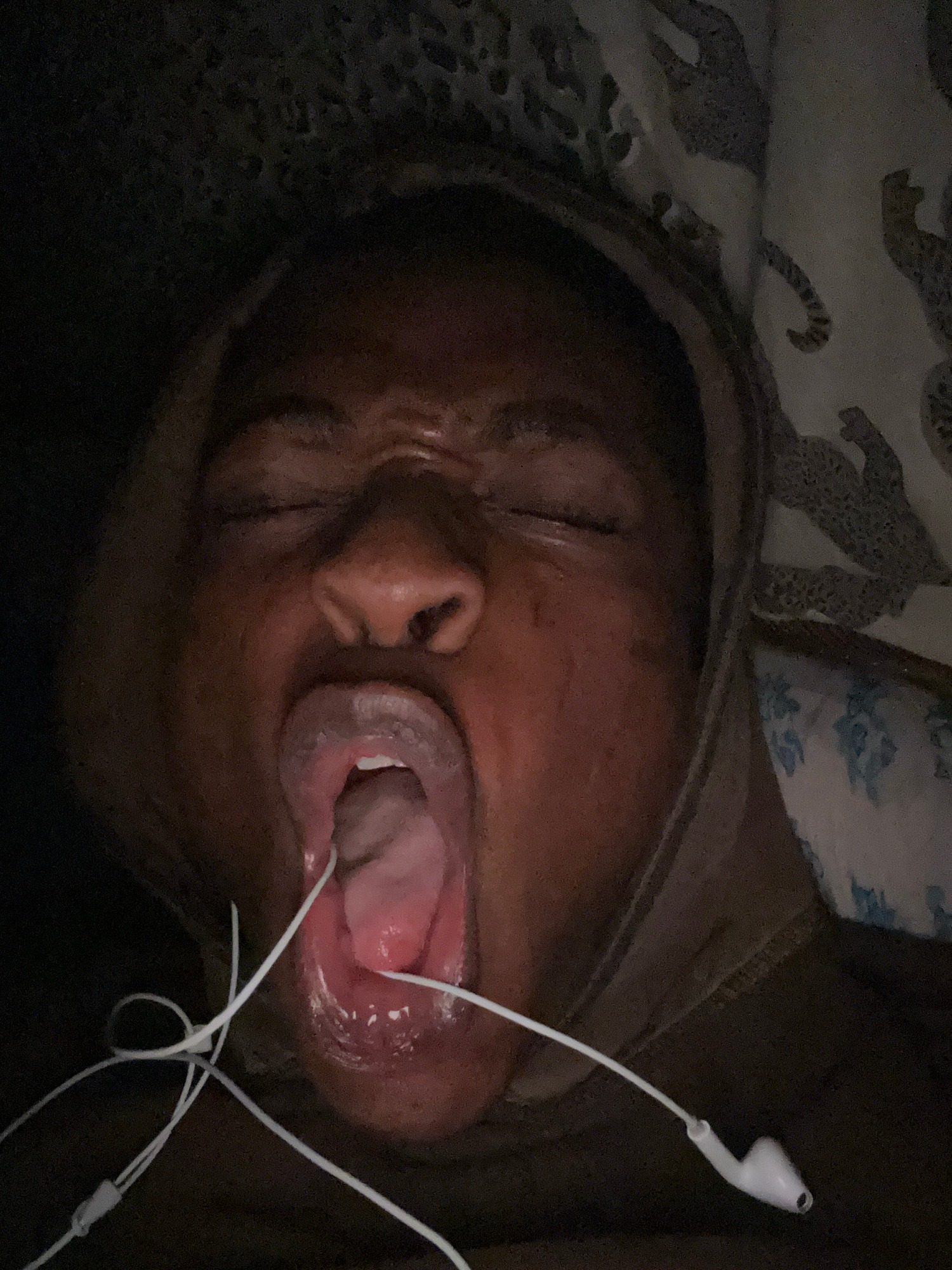 Person uses dental device in bed with earbuds