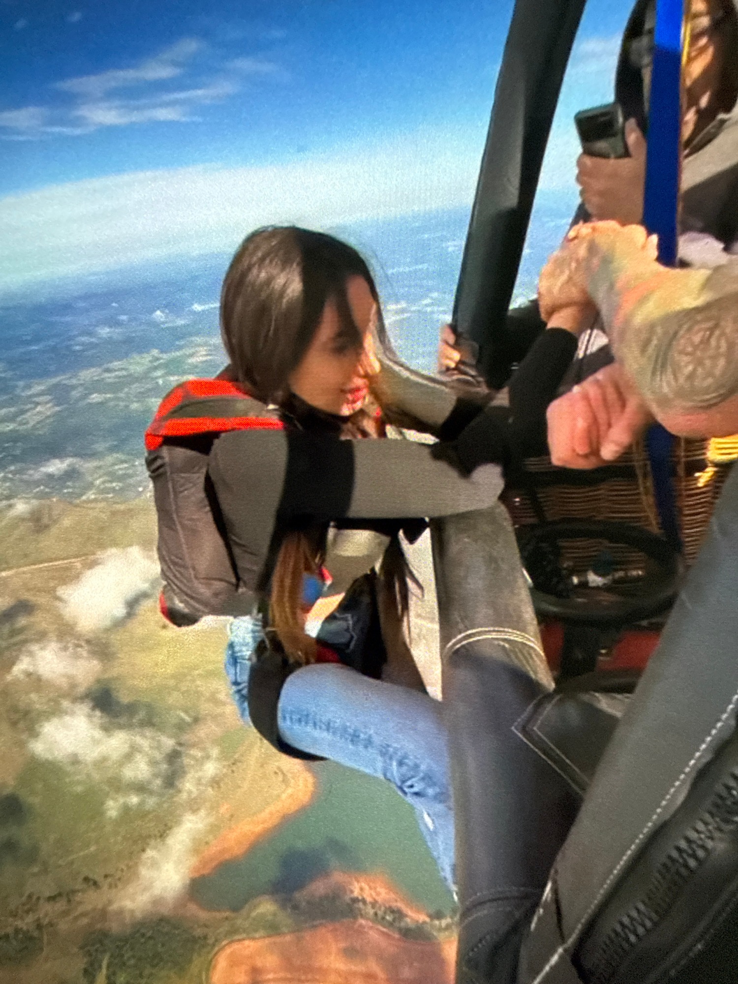 Group skydiving operation captured during helicopter jumps over city