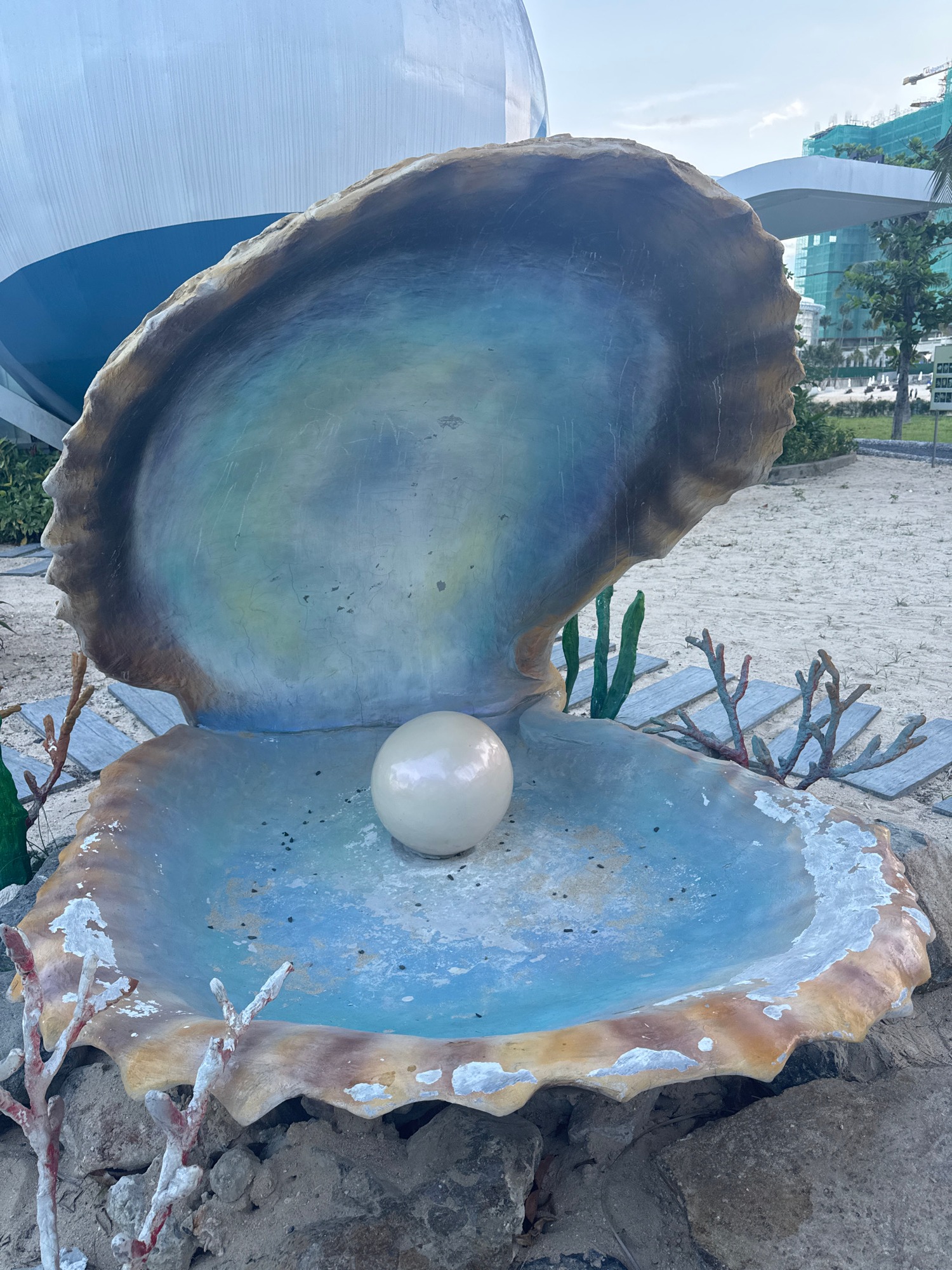 Oyster shell sculpture with pearl in sandy outdoor display