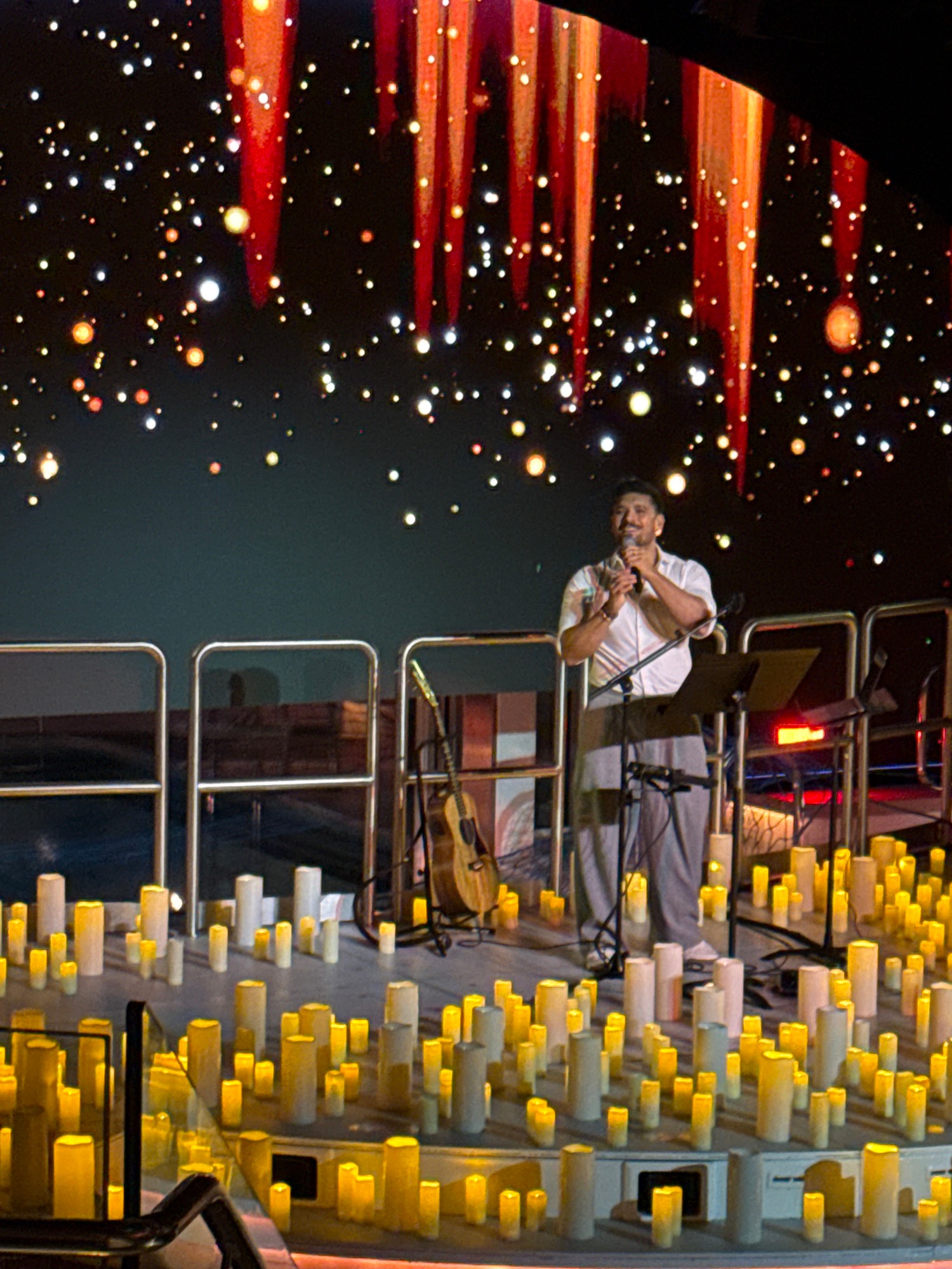 Male performer sings on stage in white shirt