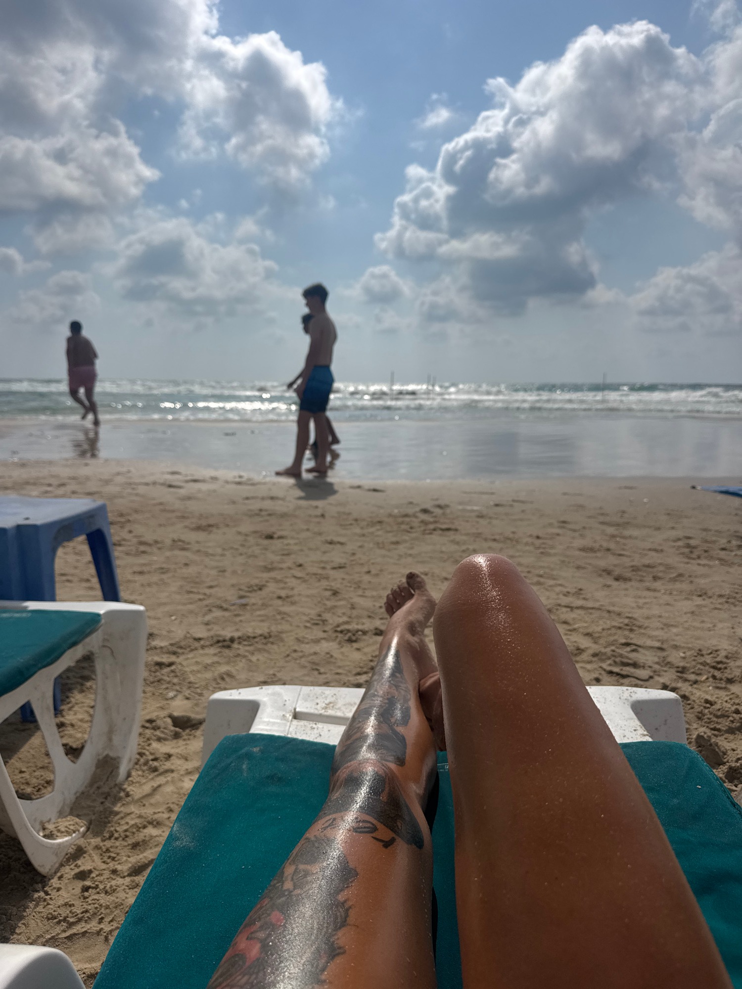 Lazy beach afternoon: lounge chair, tattoos, waves, and volleyball.