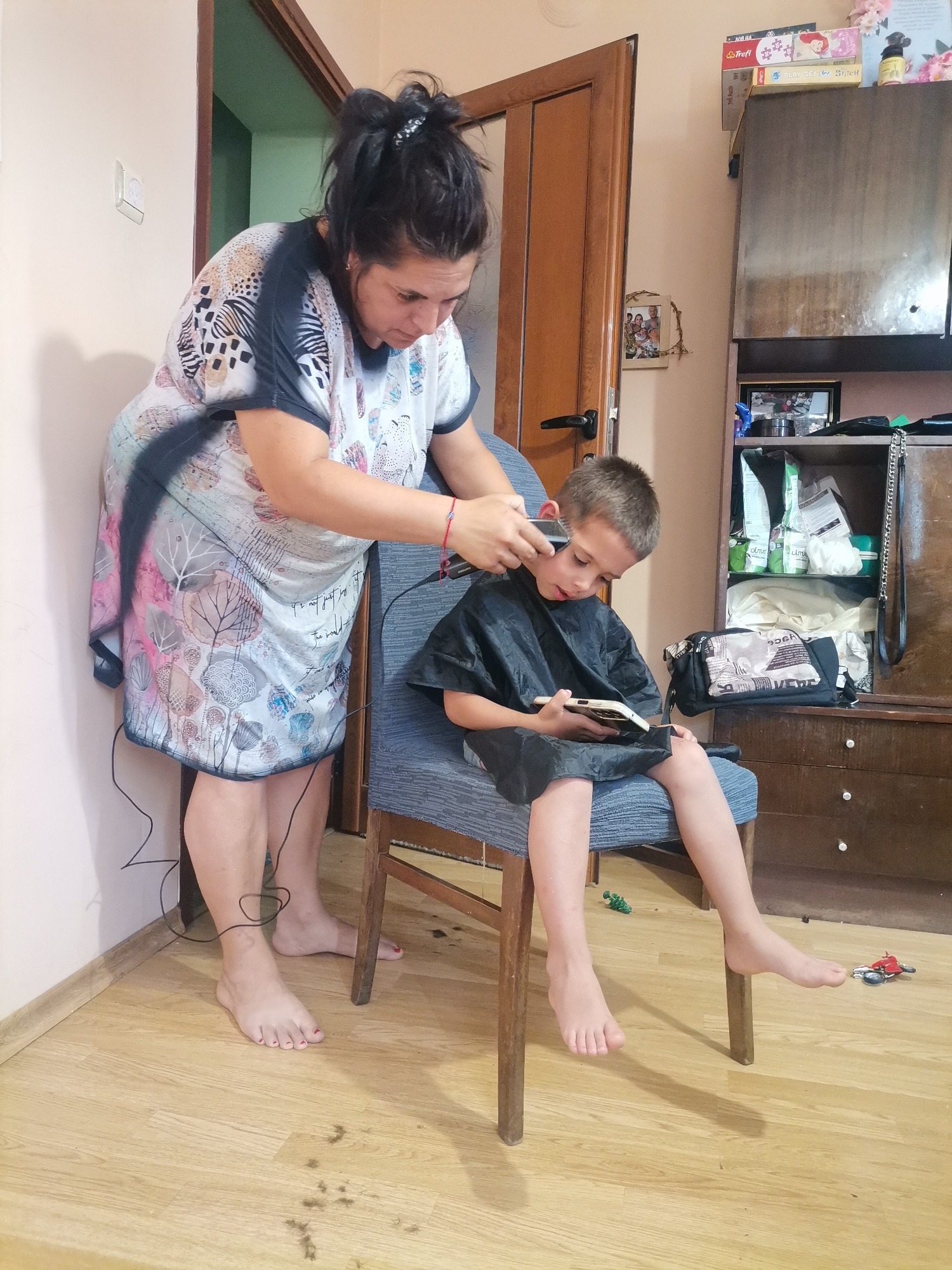 Indoor haircut session with kids relaxing nearby