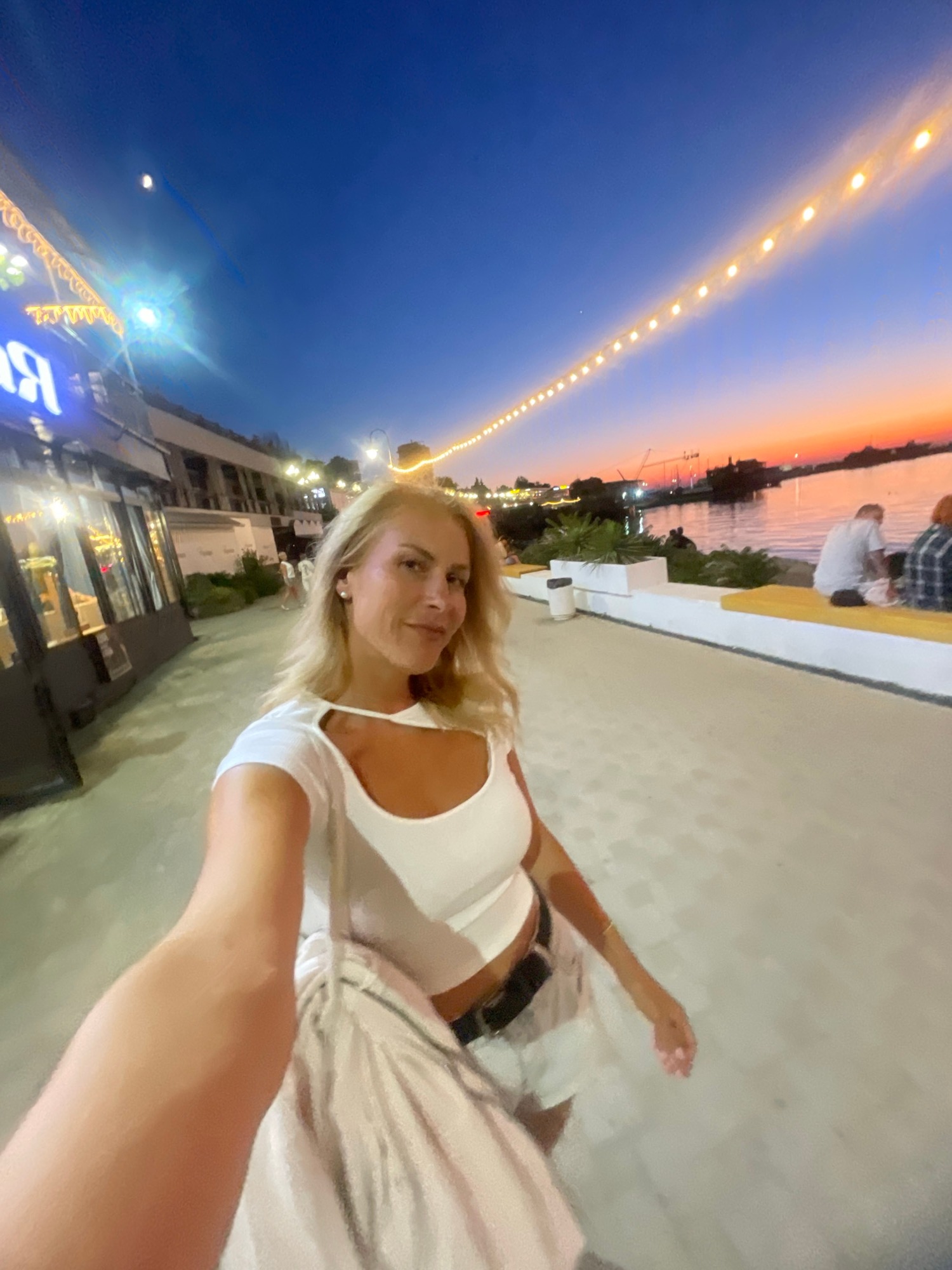 Dusk at a lively waterfront promenade with fire performance