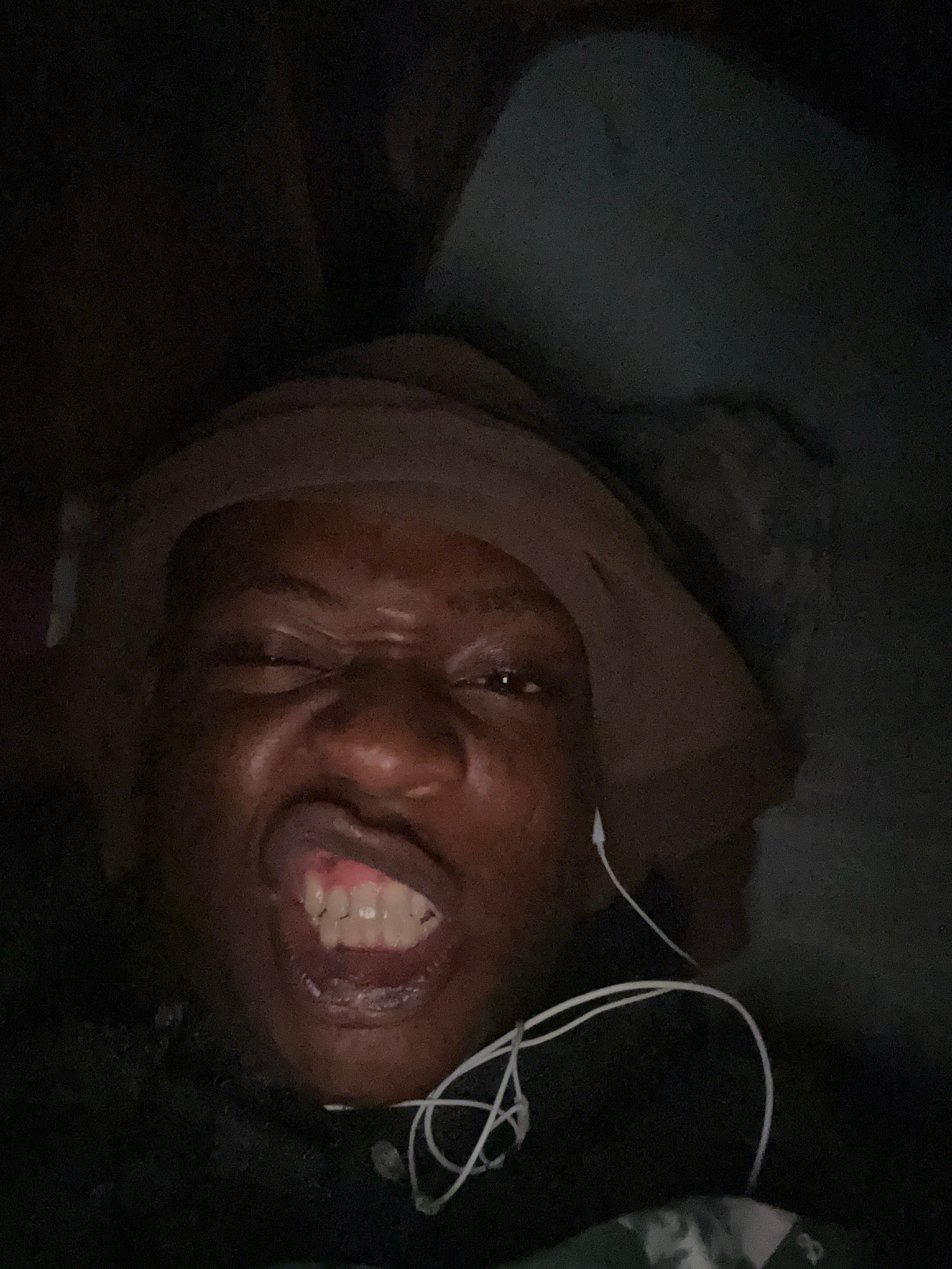 Person rests with earphones in dimly lit indoor setting