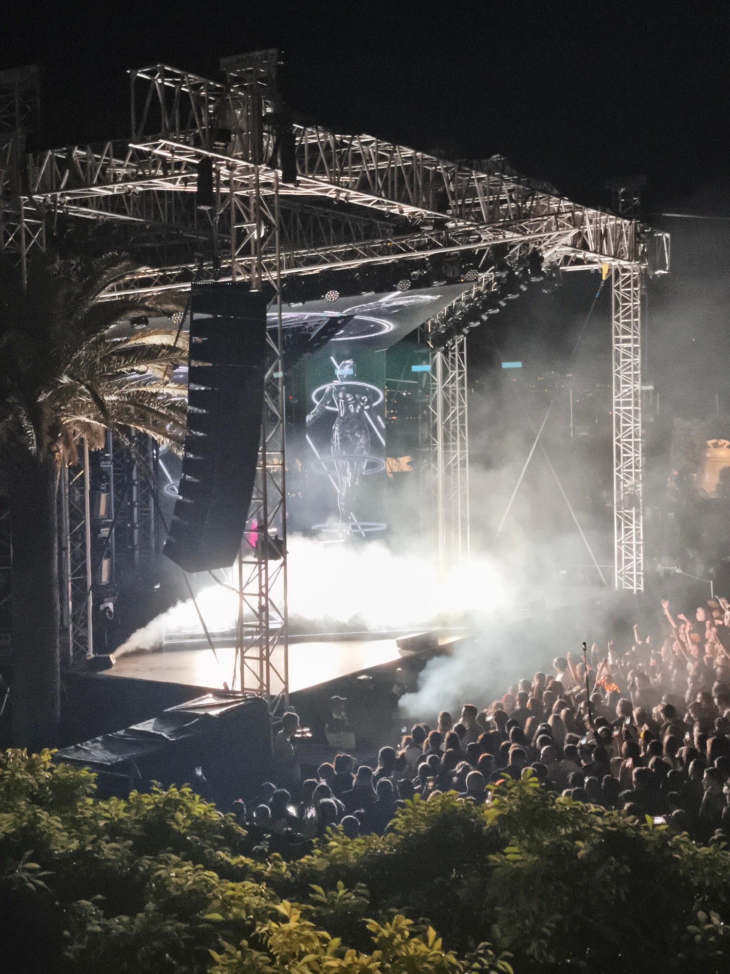Large crowd enjoys outdoor nighttime concert with stage effects